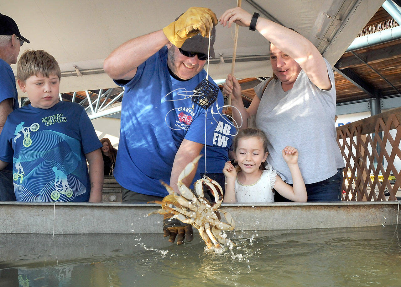 Elaina Wood, 6, center, looks on in delight after catching a crab as her brother, Kjol Wood, 11, left, watches while grandmother Tina Taylor of Port Angeles, right, and Puget Sound Anglers member Russ Manson of Sequim assist with the capture during the Grab a Crab Derby on Saturday at the Dungeness Crab and Seafood Festival in Port Angeles. The three-day festival brought abut 15,000 people to the Port Angeles waterfront for food, music and other activities. (Keith Thorpe/Peninsula Daily News)