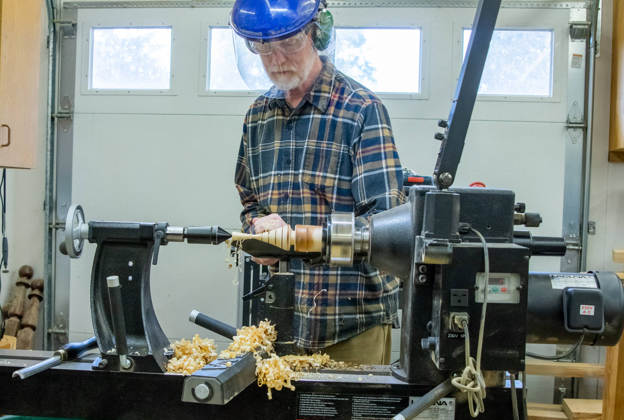 Emily Matthiessen /Olympic Peninsula News Group
Matthew Barton, membership director for the Strait Turners, demonstrates how to make a Christmas tree ornament on his lathe. He is using a a spindle roughing gouge to remove of the first layer of the wood, local cedar. His shop is large and filled with tools, but he says that beginners need only a few tools to get started and one could turn out a Christmas tree in half a day. The Strait Turners have a couple lathes that they lend to members.