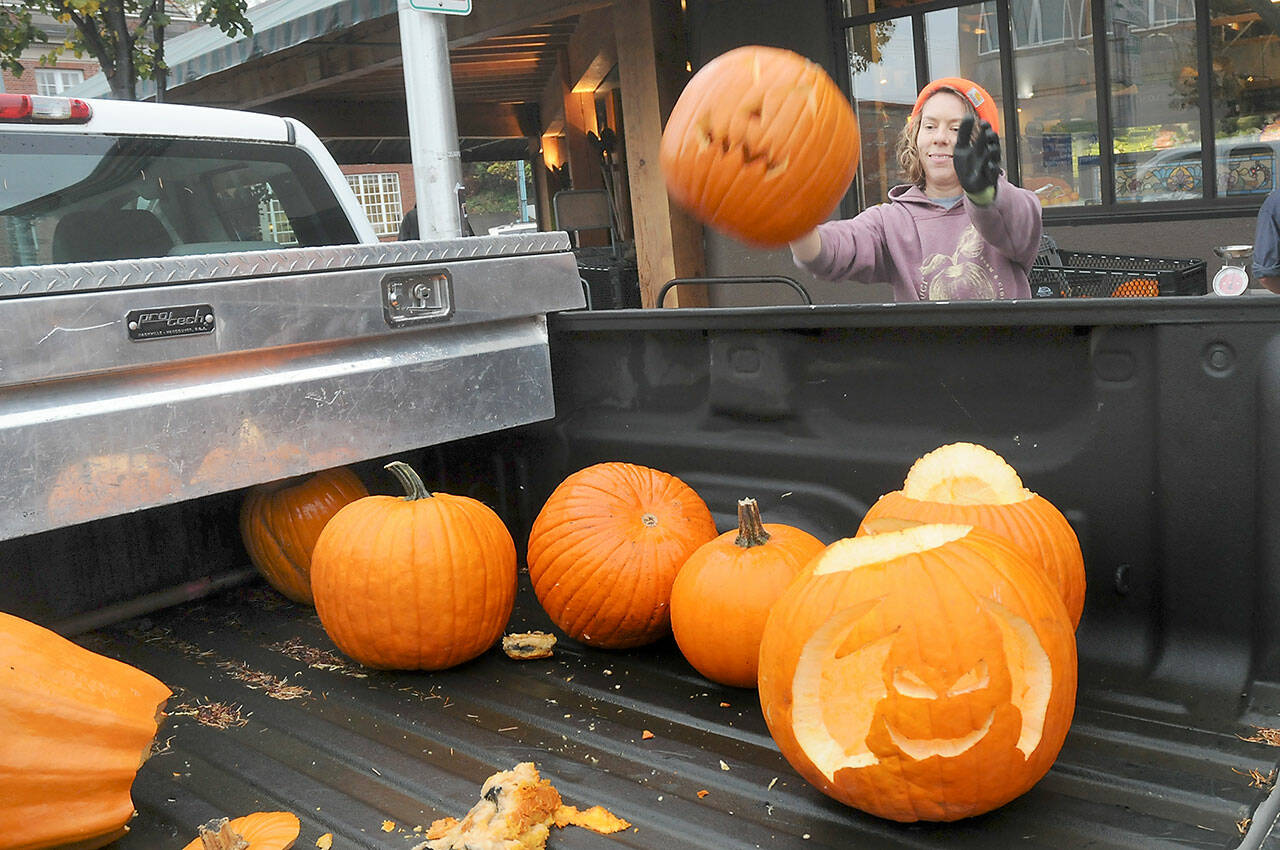 Arlene Jenson, co-founder of Sisterland Farms, tosses a used jack-o-lantern into the back of a truck for recycling during a pumpkin rescue on Friday in front of Country Aire Natural Foods in Port Angeles. The farm, with assistance from the WSU Clallam County Extension, was collecting unwanted pumpkins for composting, keeping them out of landfills and protecting the environment. (Keith Thorpe/Peninsula Daily News)