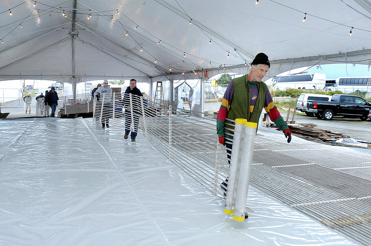 Paul Beck of Port Angeles, right, leads a line of volunteers and others as they carry a chilling element across what will become an ice skating rink on Friday at the Port Angeles Winter Ice Village. (Keith Thorpe/Peninsula Daily News)