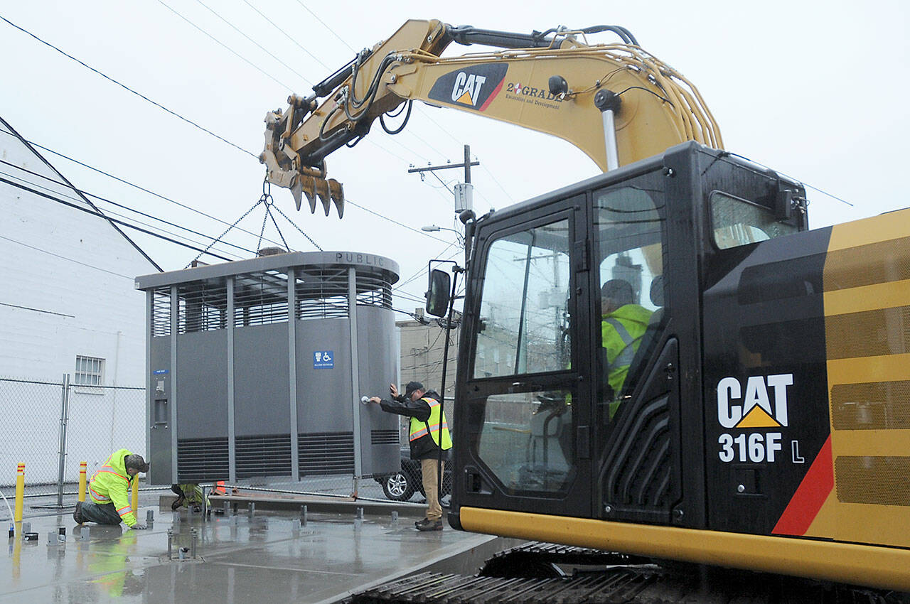 KEITH THORPE/PENINSULA DAILY NEWS
A prefabricated Portland Loo public toilet is lowered into place on a pad at the edge of the Breezeway public parking lot in the 100 block of West Front Street in downtown Port Angeles on Tuesday. The unit, one of two being installed at the location, replaces the original concrete block public restroom that previously occupied the site, with a third slated for The Gateway transit center. The new facilities are ADA-compliant, require no winterization and will be open to the public 24 hours a day, seven days a week.