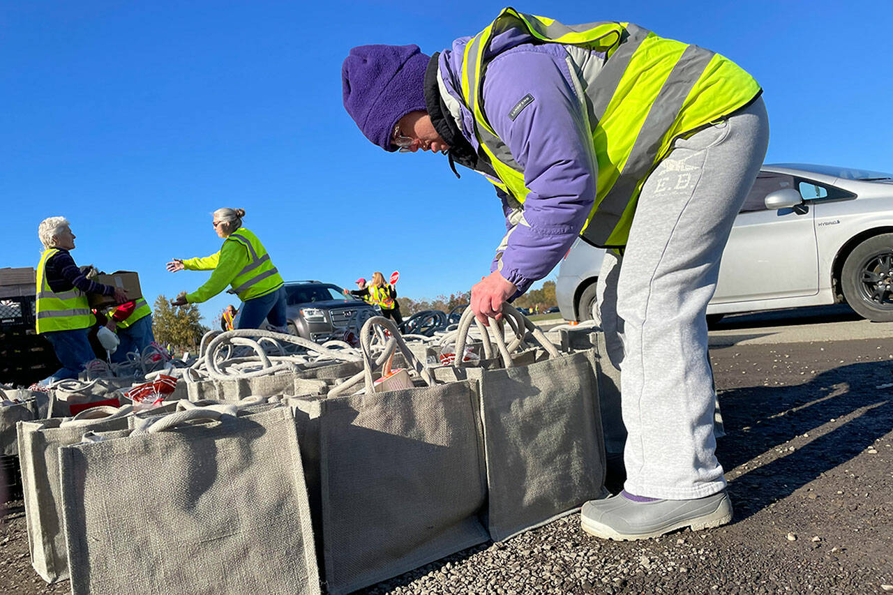 Megan Caldwell returns to Carrie Blake Community Park to work with her dad Bert to help place meal bags in vehicles during the Family Holiday Food Bag Distribution Day. (Matthew Nash/Olympic Peninsula News Group)