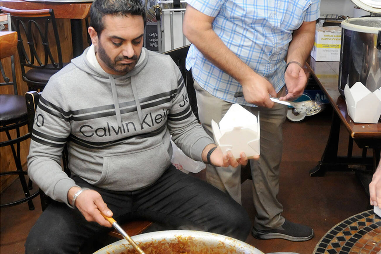 KEITH THORPE/PENINSULA DAILY NEWS
Harry Nagra, left, and Harry Sangha, owners of Hardy’s Market in Sequim, dish out dinner boxes of Biryani chicken and rice for the market's annual Thanksgiving Day meal giveaway. The meals also included slices of pumpkin pie for distribution to hungry diners.