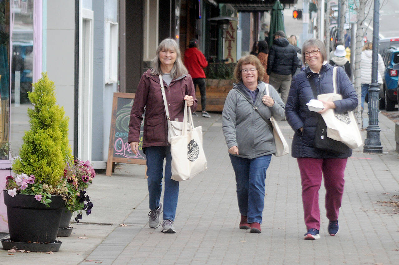 Shoppers, from left, Sue Priest, Pam Predovich and Peggy Romero, all of Port Angeles, stroll down West First Street in downtown Port Angeles searching for bargains on Small Business Saturday, a local followup to Black Friday, kicking off the holiday shopping season. Weekend shoppers were given an opportunity to purchase tote bags containing coupons for special deals from participating merchants, with proceeds from tote sales benefiting the Port Angeles Winter Ice Village. (Keith Thorpe/Peninsula Daily News)