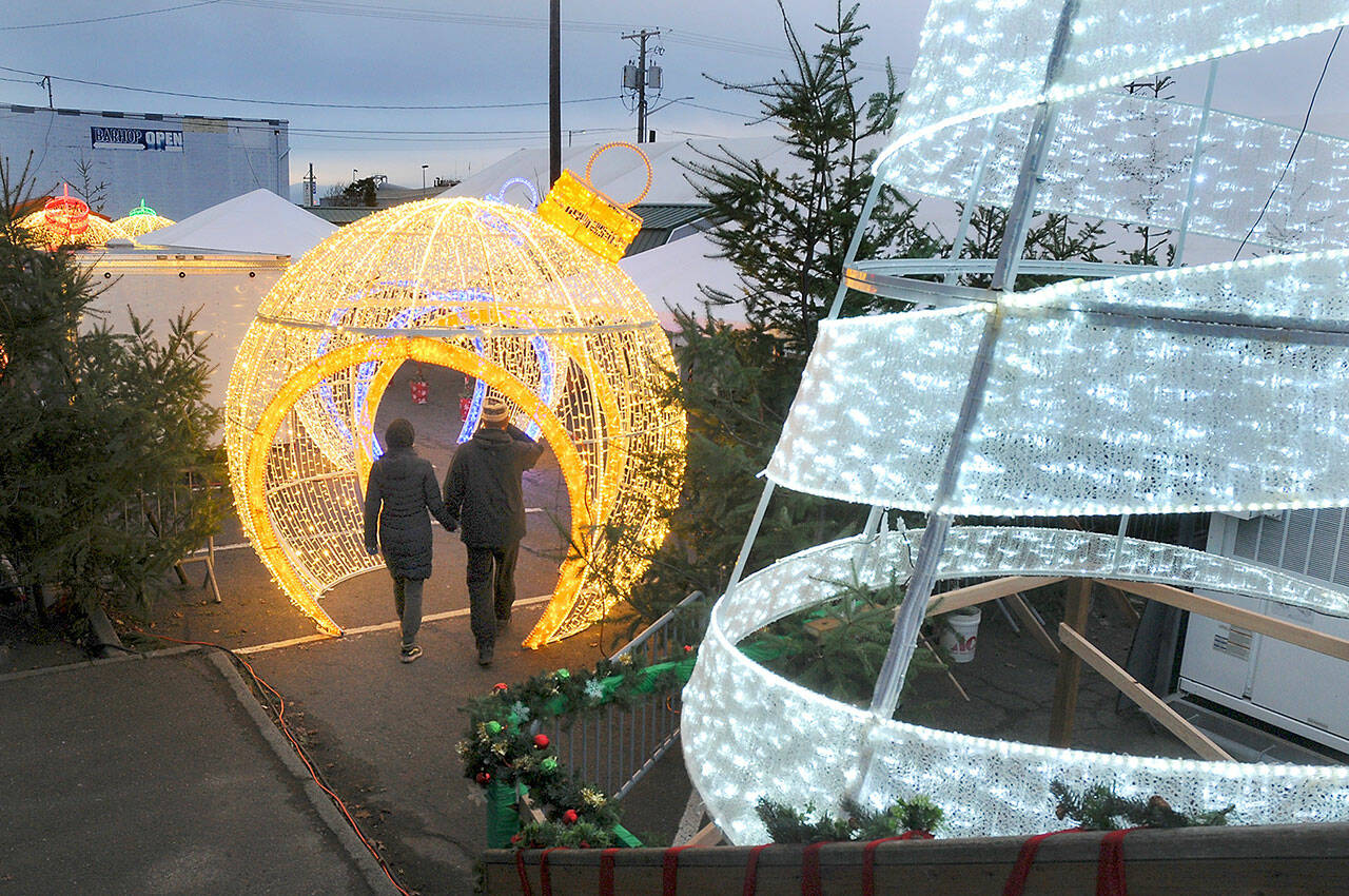 Visitor to the Port Angeles Winter Ice Village walk through a decorative ornament, part of a donation of holiday decorations from the Microsoft Corporation to the Olympic Medical Center Foundation for use at last weekend’s Festival of Trees, and then moved to the ice village for the duration of the ice skating season. The villages offers daily skating through Jan. 2 in downtown Port Angeles. (KEITH THORPE/PENINSULA DAILY NEWS)