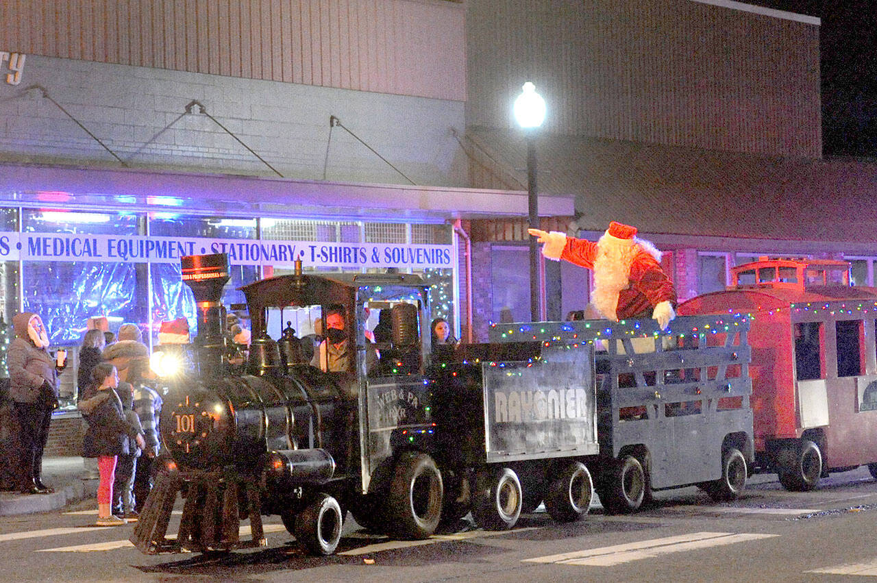 Santa tides down Forks Avenue in the West End Business Professional Association train on Saturday evening during the 21st annual Twinkle Light Parade before lighting the Forks Community Tree at the intersection of Sol Duc Way and Forks Avenue. Before and after the parade, the public viewed the Soroptimist International of the Olympic Rain Forest’s annual Festival of Trees. Trees were auctioned off Sunday. (Lonnie Archibald/for Peninsula Daily News)