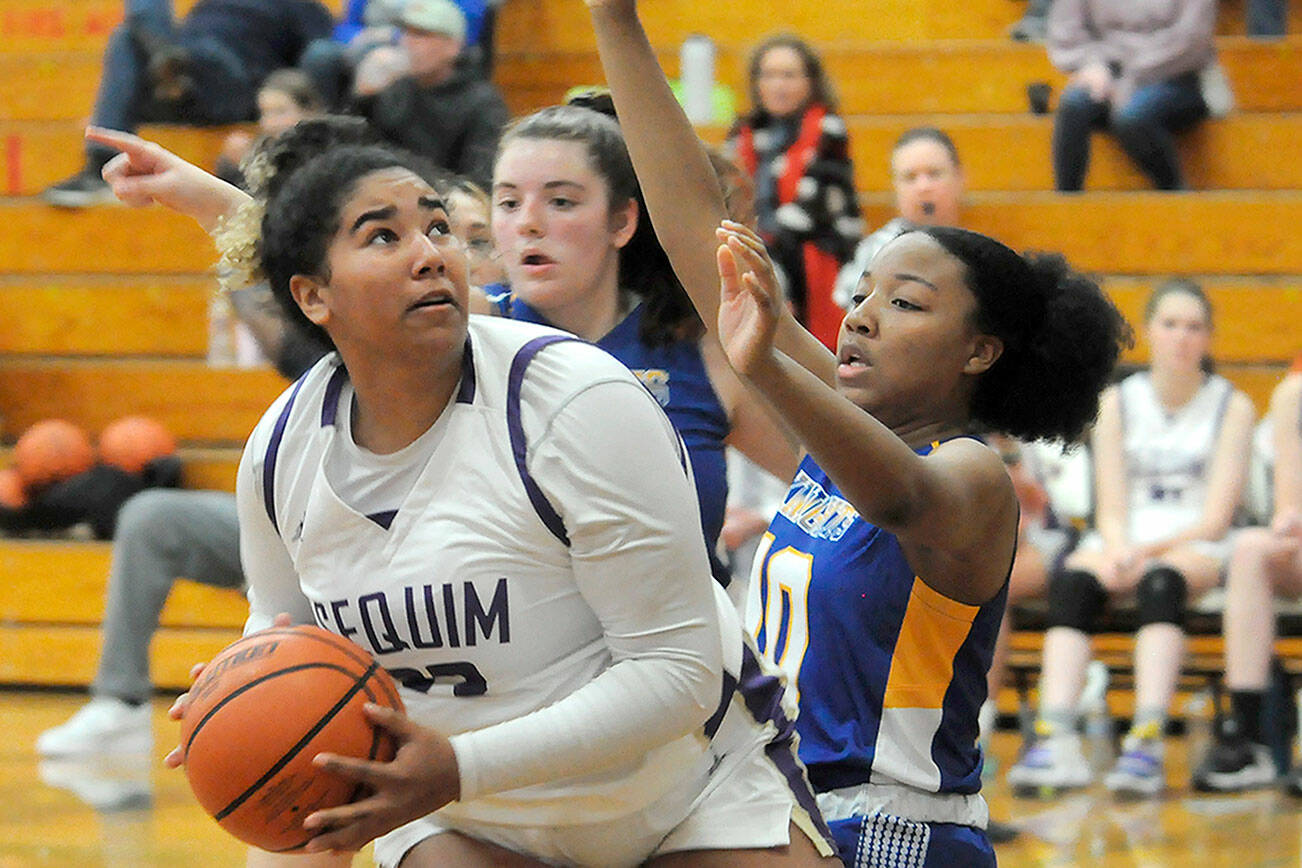 Matthew Nash/Olympic Peninsula News Group
Sequim's Jelissa Julmist eyes the rim while double teamed during the Wolves' 56-43 win Thursday.