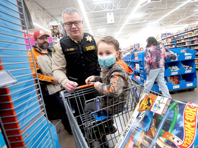 Brian King, the chief criminal deputy for the Clallam County Sheriff’s Office, is among more than 100 volunteers from a dozen agencies to participate in the Shop with a Hero program at Wal-Mart in Port Angeles. About 80 kids from the community got to go on a shopping spree with law enforcement officers from Port Angeles, Sequim and other agencies and spend $100 however they wished. They also had a chance to take photos with Santa, sip on hot chocolate, decorate cookies and see police vehicles up close. (Jesse Major/for Peninsula Daily News)
