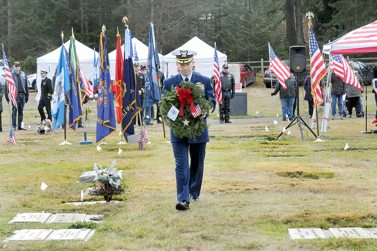 Cmdr. Brian Tesson, commanding officer of the U.S. Coast Guard Cutter Active, carries a wreath for the grave of Coast Guard veteran Harold Hanusa, who served during World War II, during Saturday’s Wreaths Across America ceremony at Mount Angeles Memorial Park in Port Angeles. The event, part of a national initiative to honor veterans of military service, saw individual branches of the military recognized during the ceremony followed by the placement of more than 2,300 wreaths for servicemen and women at six cemeteries across the North Olympic Peninsula. (Keith Thorpe/Peninsula Daily News)