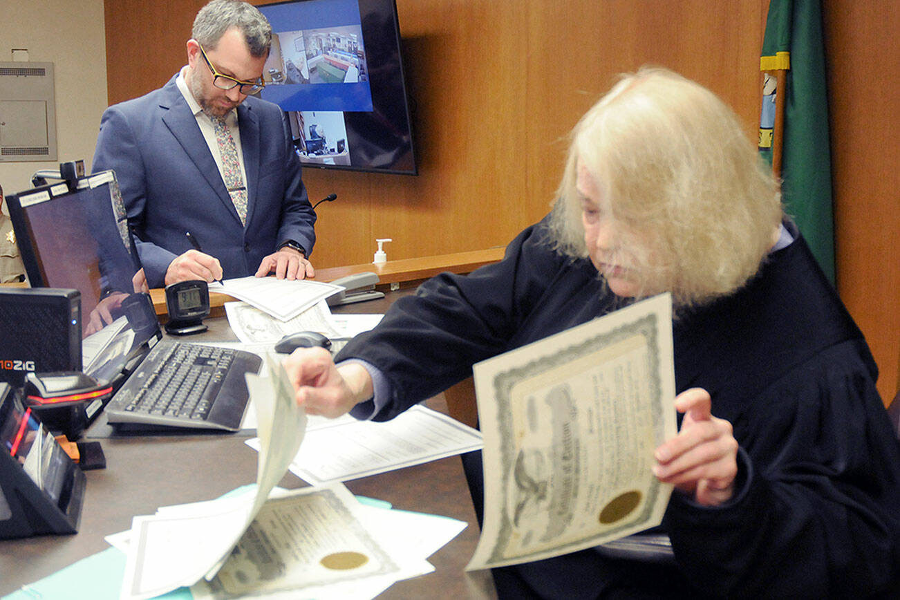 Newly elected Clallam County Commissioner Mike French, left, signs documents as Clallam County Superior Court Judge Lauren Erickson sorts election certificates during a swearing-in ceremony on Wednesday at the Clallam County Courthouse in Port Angeles. (Keith Thorpe/Peninsula Daily News)