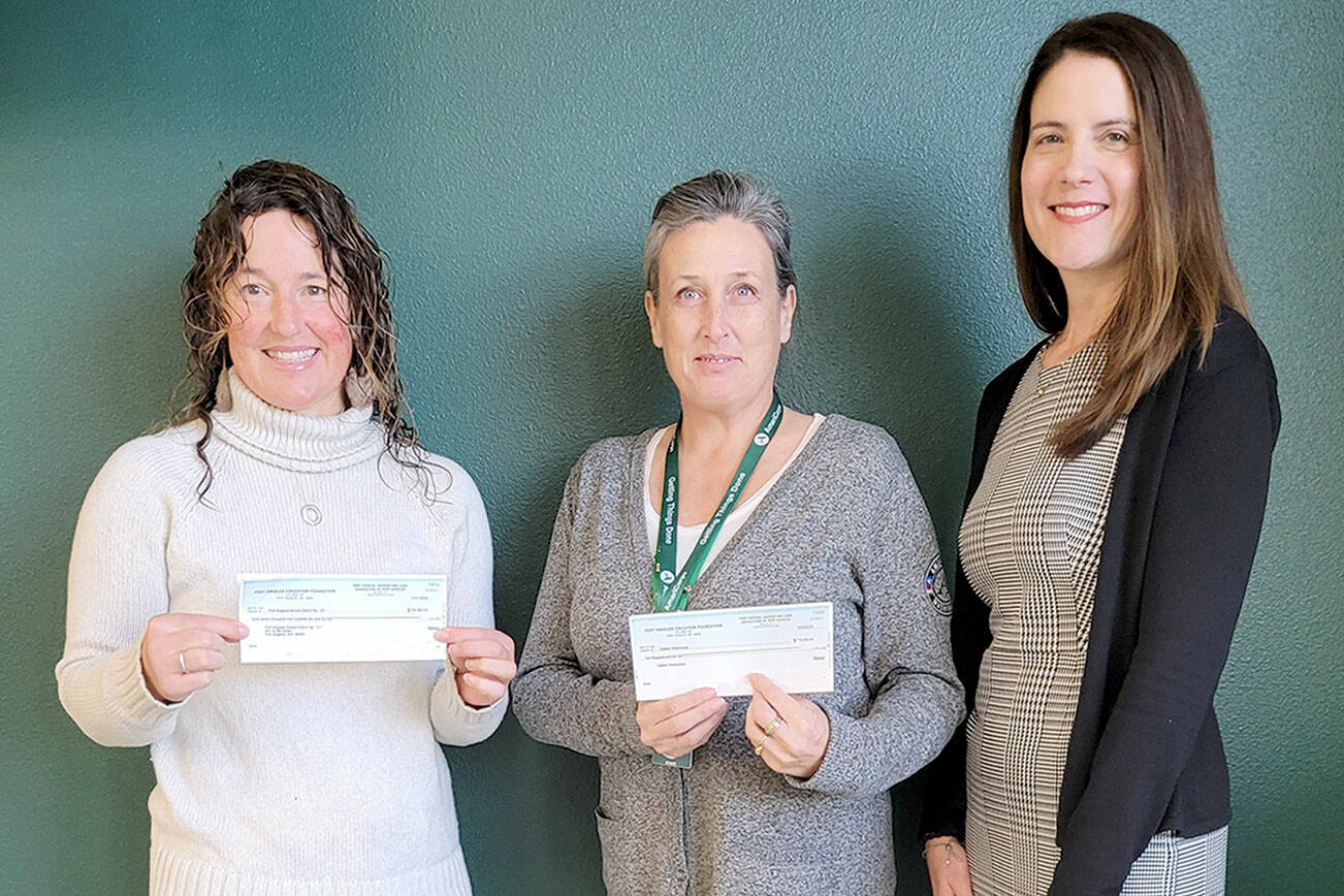 Port Angeles Education Foundation Board President Michelle Turner, on left, presents checks to Michell Gentry, AmeriCorps program director and Kira Acker, Port Angeles School District business and operations director, on right.