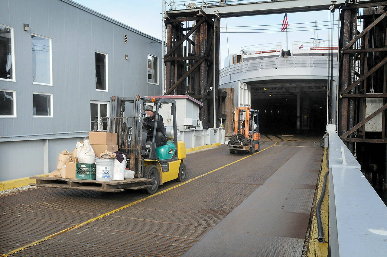 Able seamen Doug Reader, front, and Brandon Melville drive forklifts as they offload equipment from the ferry MV Coho after its return to Port Angeles from annual dry dock maintenance in Anacortes on Wednesday. The ferry is scheduled to resume regular service between Port Angeles and Victoria today. (Keith Thorpe/Peninsula Daily News)