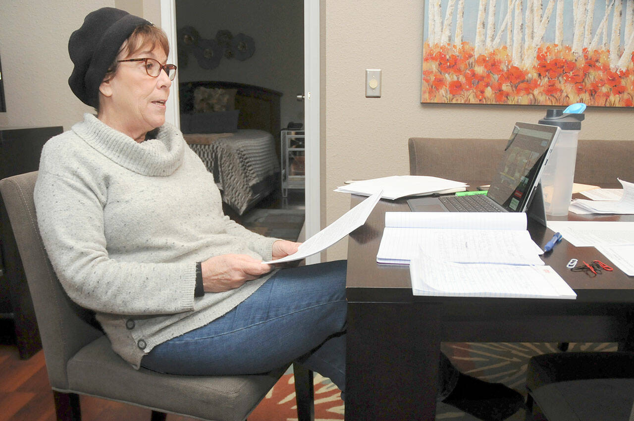 Keith Thorpe/Peninsula Daily News
Manufactured home owner Chris Walker of Sequim goes over paperwork while watching an internet-streamed hearing on rent increases in mobile and modular home communities.