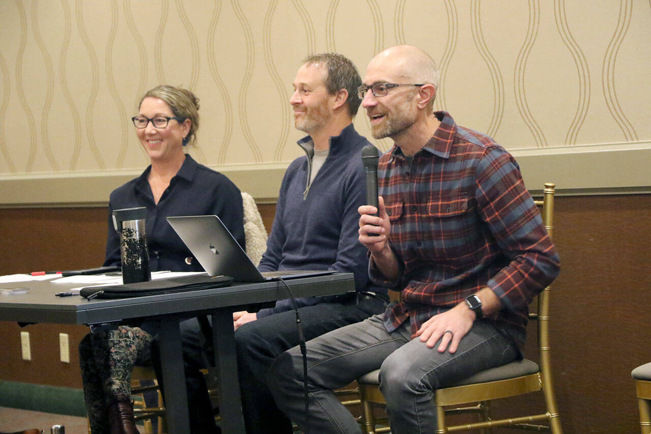 4PA founder Joe DeScala, far right, speaks to a group of about 50 people during a town hall meeting, sitting with board members Justine Snook, center, and Jessica Irvine, left. (Ken Park/Peninsula Daily News)