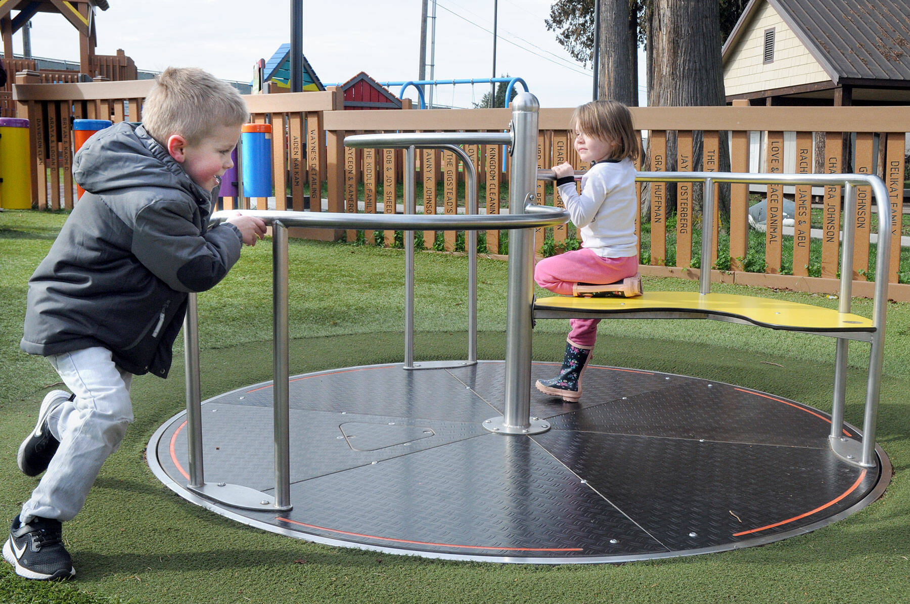 Braxton Stewart, 3, of Mill Creek pushes a merry-go-round as Kiara Ann, 4 of Sequim gets a free ride on Wednesday at the Dream Playground at Erickson Playfield in Port Angeles. The pair were enjoying a cool but clear late-winter day on the North Olympic Peninsula. (Keith Thorpe/Peninsula Daily News)
