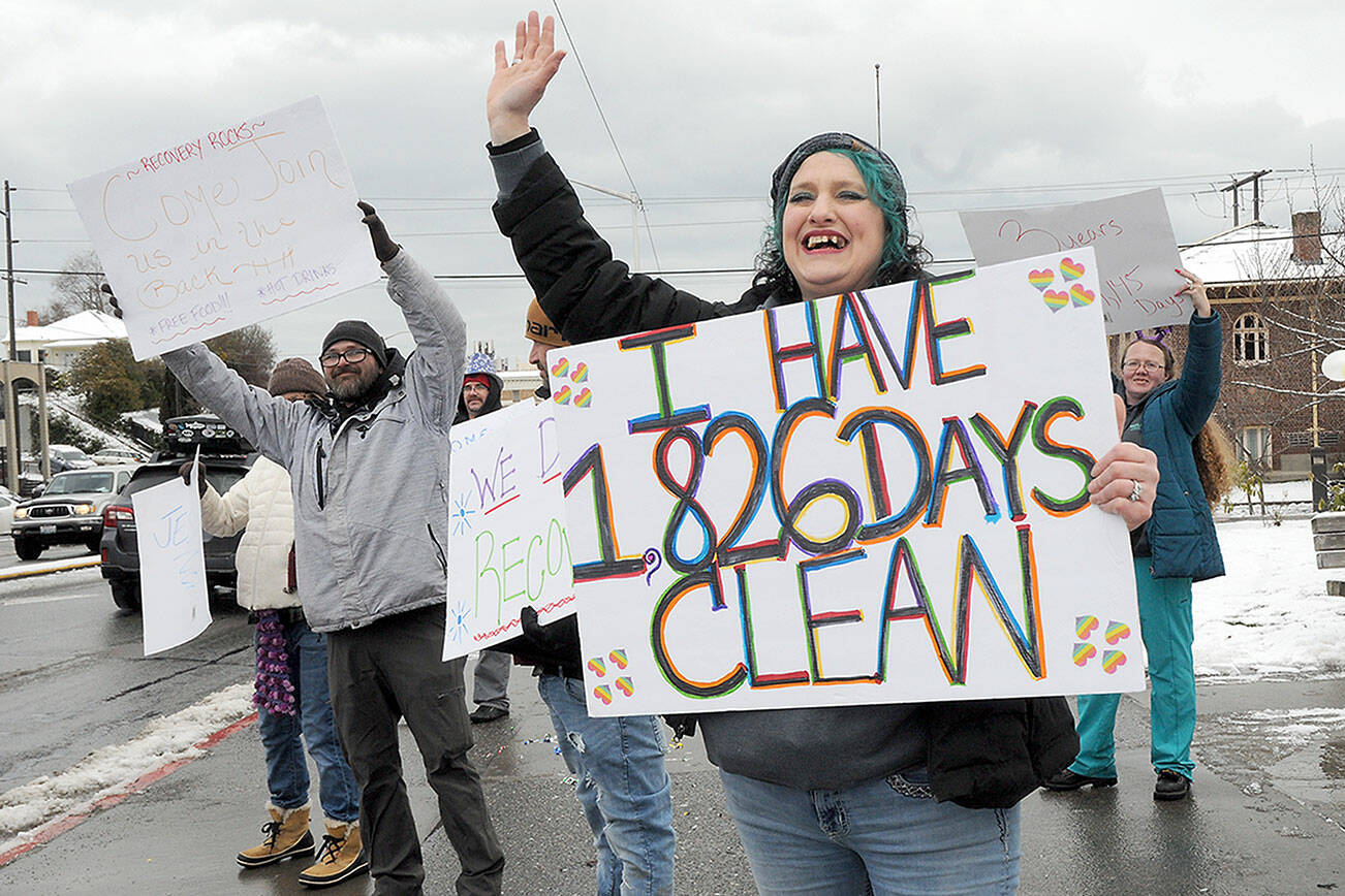KEITH THORPE/PENINSULA DAILY NEWS
Jenni Tiderman of Port Angeles, front, holds a sign celebrating her five years of addiction recovery during "birthday bash" and resource fair hosted by Reflections Counseling Services Group on Thiursday at Veterans Park in Port Angeles. The event featured representatives from numerous drug and alcohol addiction and homelessness support agencies, as well as free meals and clothing for those in need.