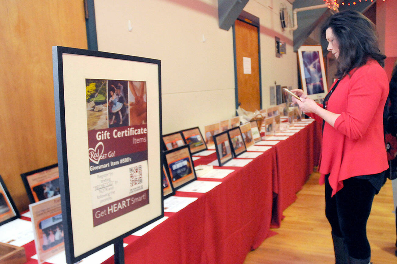 KEITH THORPE/PENINSULA DAILY NEWS
Vicki Wallner, a representative of the Jamestown S'Klallam Tribe, examinmes displays of gift certificates for goods and services available at a silent auction during the Red, Set Go! Heart Luncheon on Friday at Vern Burton Community Center in Port Angeles. The event, presented by the Jamestown tribe, served to raise awareness of heart health for women and as a fundraiser for the Olympic Medical Center's Heart Center.