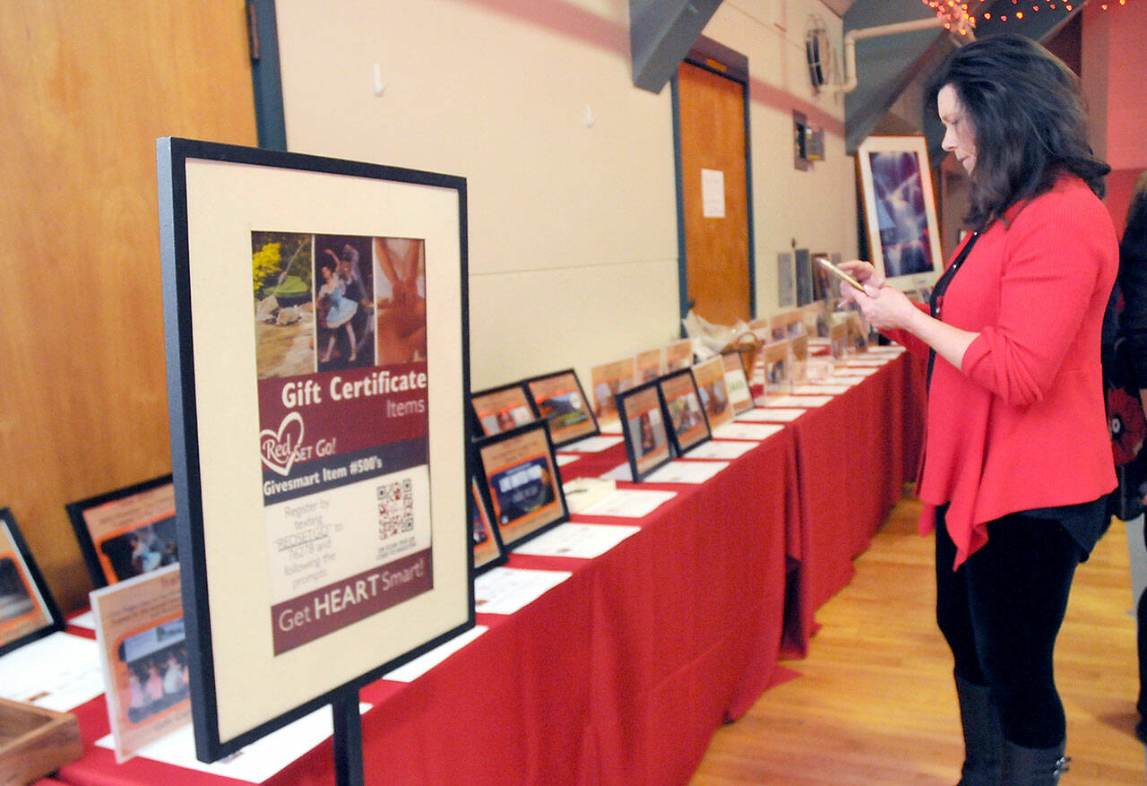 Vicki Wallner, a representative of the Jamestown S’Klallam Tribe, examinmes displays of gift certificates for goods and services available at a silent auction during the Red, Set Go! Heart Luncheon on Friday at Vern Burton Community Center in Port Angeles. The event, presented by the Jamestown tribe, served to raise awareness of heart health for women and as a fundraiser for the Olympic Medical Center’s Heart Center. (KEITH THORPE/PENINSULA DAILY NEWS)