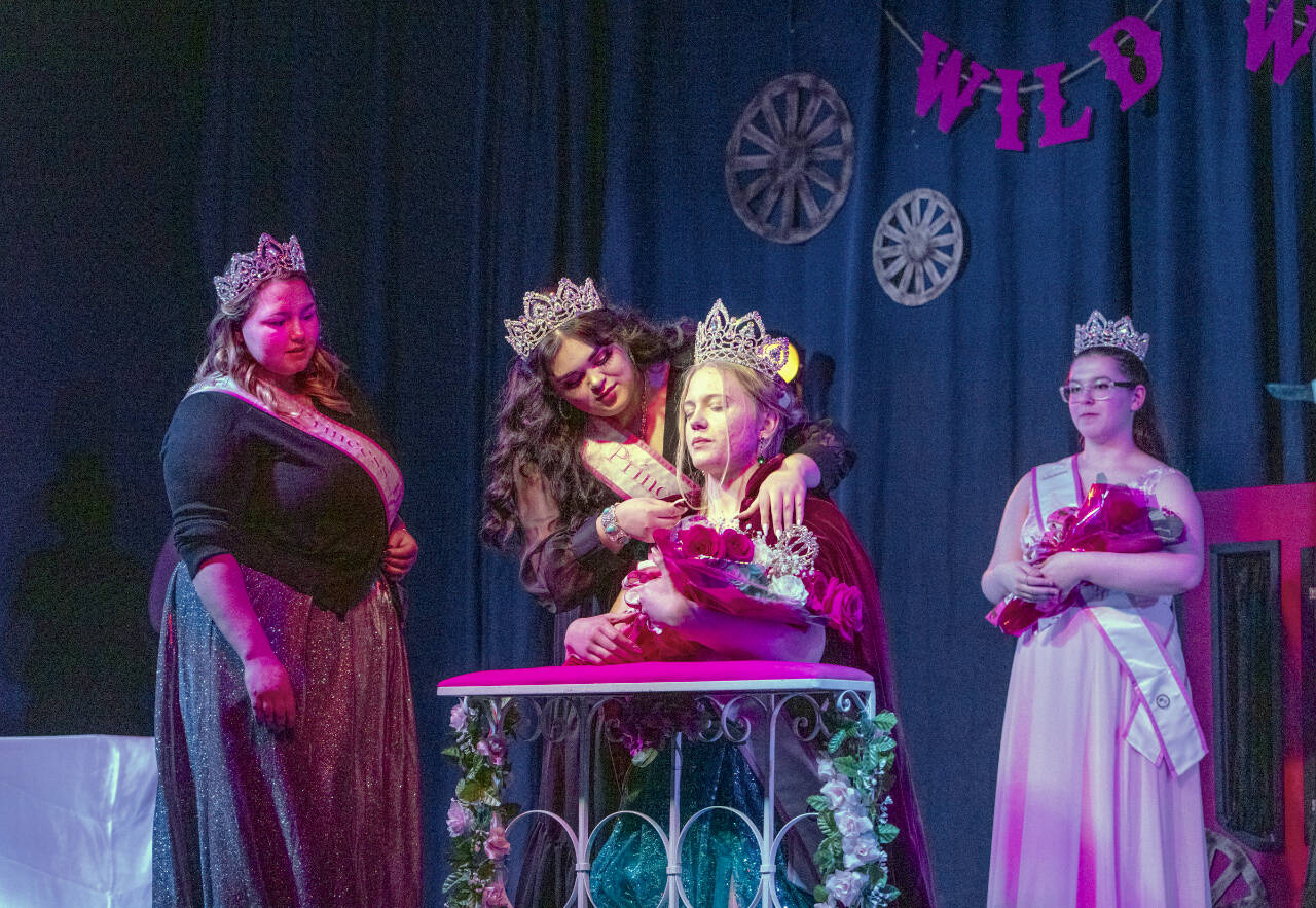 With 2022 Princess Hailey Palmer, left, and 2023 Princess Paige Govia, right, looking on, the newly crowned 2023 Rhody Queen Melody Douglas accepts the cloak of office from 2022 Princess Hailey Hirschel during a coronation at the Jefferson County Fairgrounds on Sunday. (Steve Mullensky/For Peninsula Daily News)