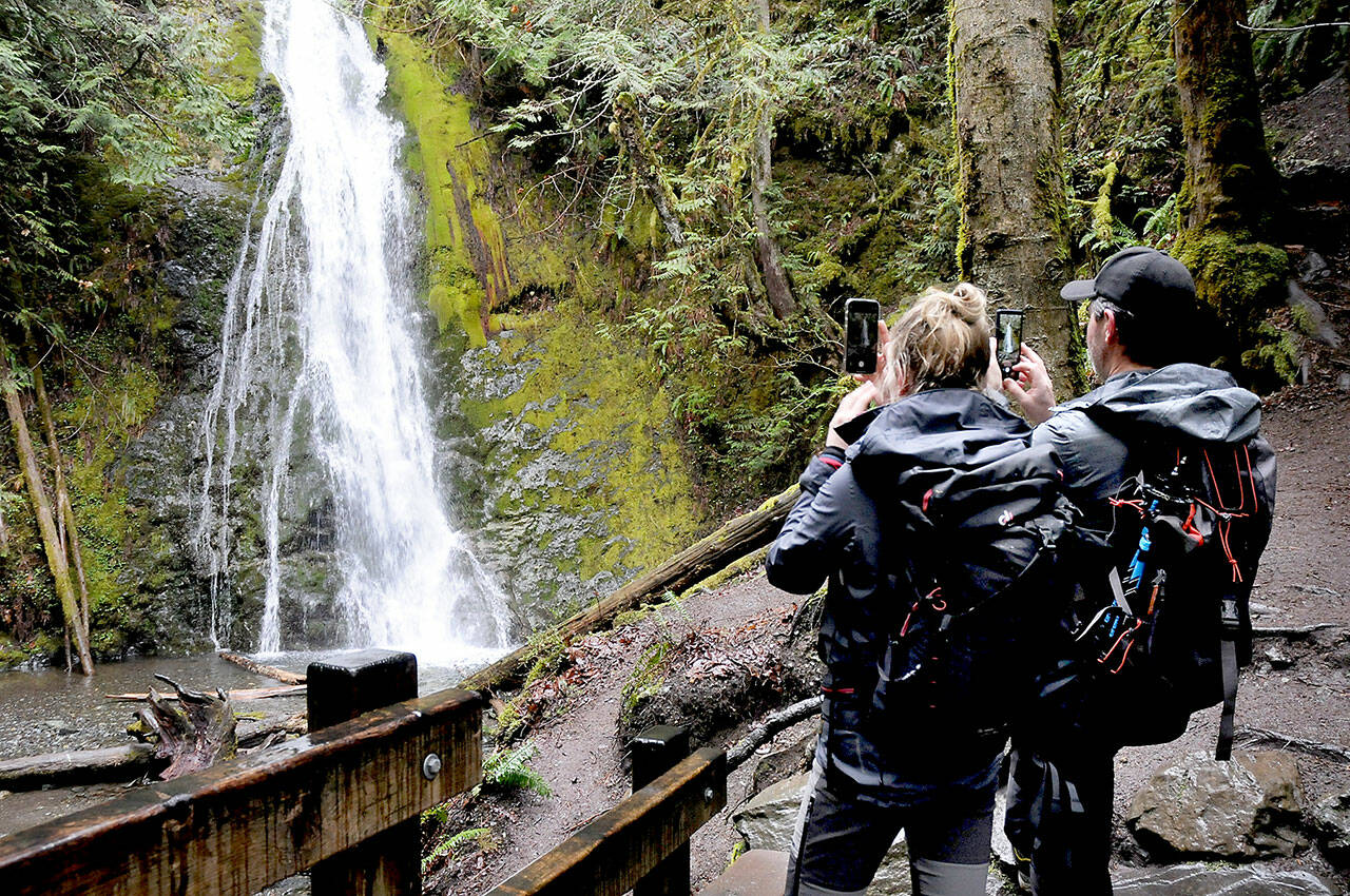 Larissa Lupp of Frankfurt, Germany, left, and Alex Nebel of Graz, Austria, take cellphone photos of Madison Creek Falls on the north edge of Olympic National Park on Friday. The pair were exploring features of the Elwha River Valley southwest of Port Angeles during a visit to the park. (Keith Thorpe/Peninsula Daily News)
