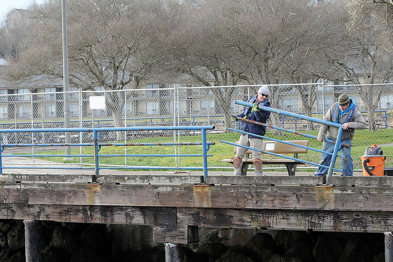 KEITH THORPE/PENINSULA DAILY NEWS
Brian Tucker, left, and Kevin Smith, workers with the Sequim branch of Neely Construction Co., remove a section of rusted railing at Port Angeles City Pier on Thursday.. The project calls for replacement of 1,300 linear feet of pedestrian railings that were installed in the 1970s with corrosion-resistant galvanized steel barriers around the pier and walkways. The project is expected to be completed in June.