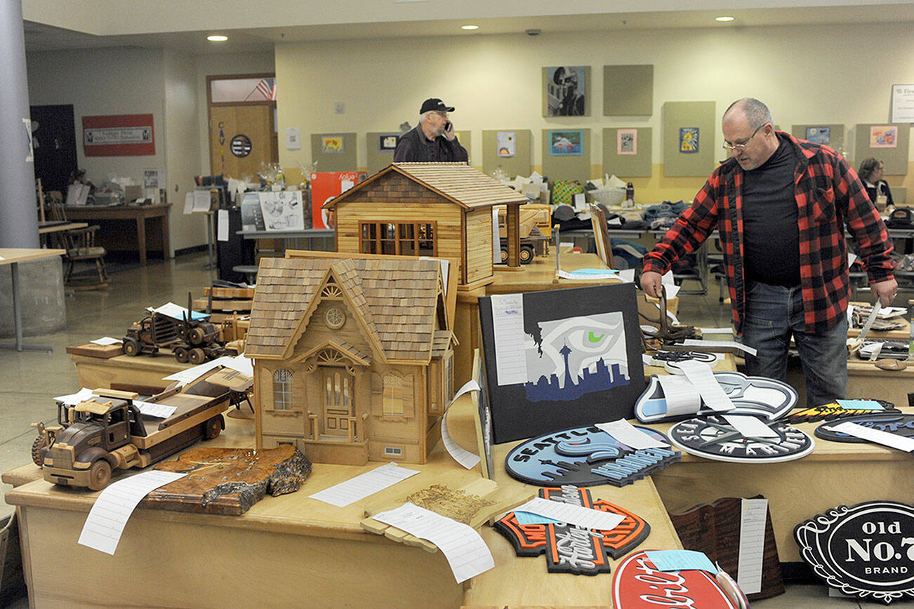 Jon Buonpane of Forks looks over a few of the many wooden items — many made by Olympic Corrections Center inmates — featured during the 2023 Quillayute Valley Scholarship Auction on Saturday. The auction, which continued on Sunday, offered more than 1,000 items to raise money for scholarships for Forks High School graduates. The annual event was accompanied this year by the inaugural Forever Twilight in Forks Equinox, which ran from Friday through Sunday. (Lonnie Archibald/for Peninsula Daily News)