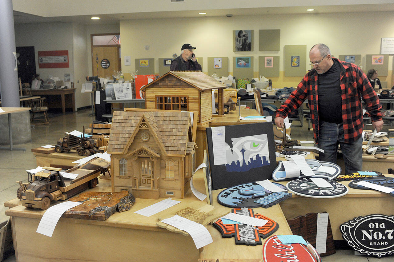 Jon Buonpane of Forks looks over a few of the many wooden items — many made by Olympic Corrections Center inmates — featured during the 2023 Quillayute Valley Scholarship Auction on Saturday. The auction, which continued on Sunday, offered more than 1,000 items to raise money for scholarships for Forks High School graduates. The annual event was accompanied this year by the inaugural Forever Twilight in Forks Equinox, which ran from Friday through Sunday. (Lonnie Archibald/for Peninsula Daily News)