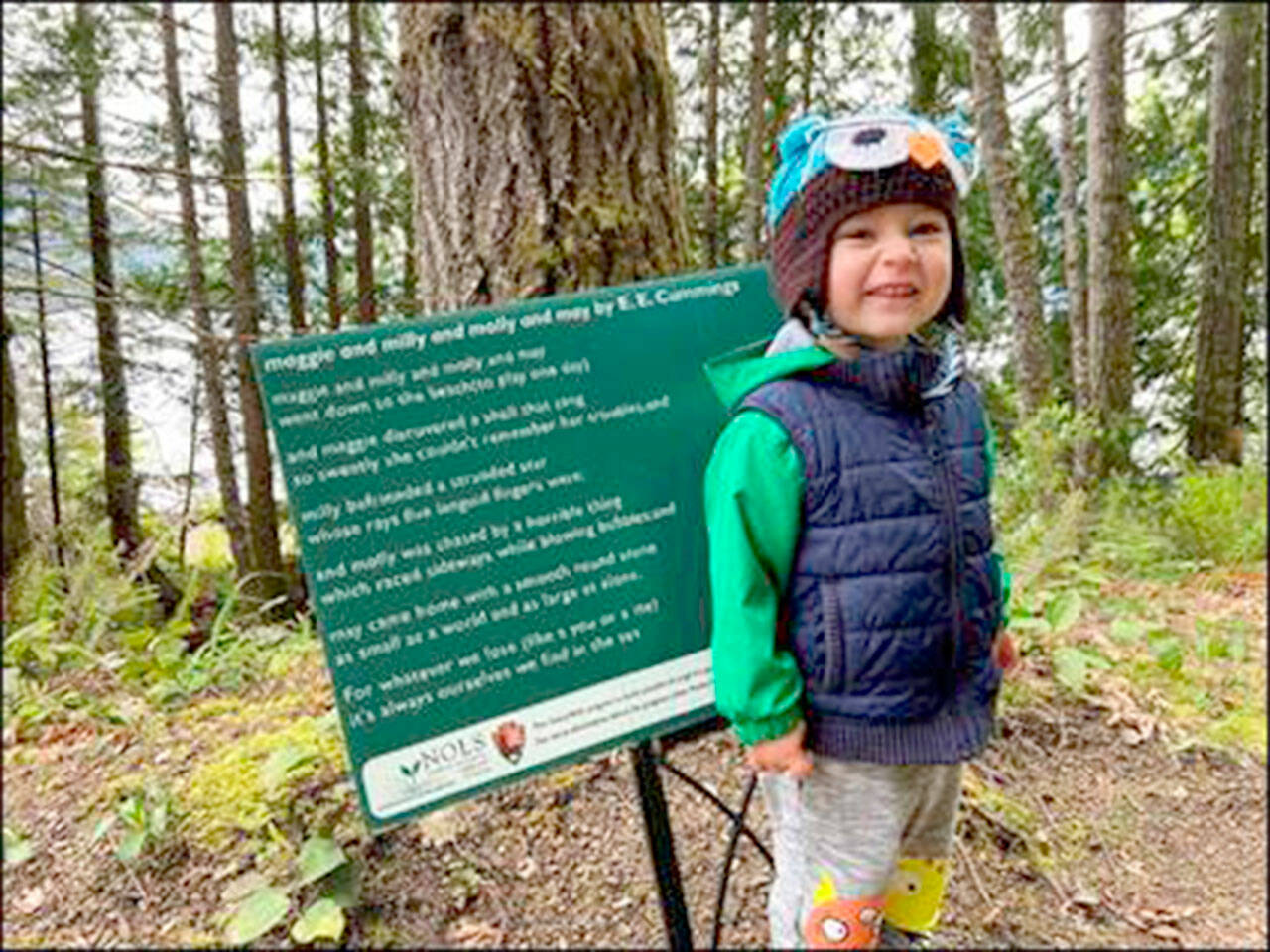 Julie McCord Brân McCord stands before a poem at the Spruce Railroad Trail in 2022.