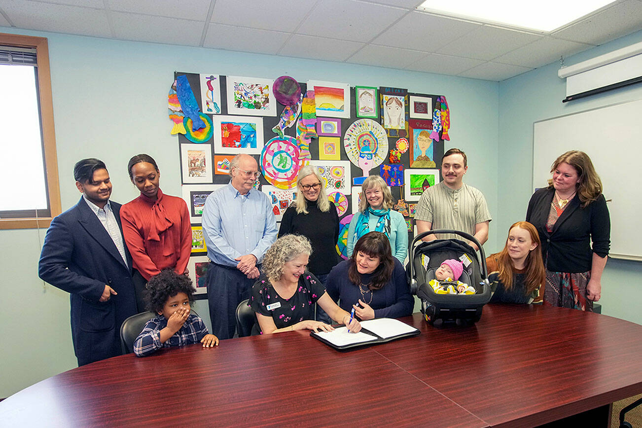Steve Mullensky/for Peninsula Daily News

Wendy Bart, representing the YMCA, signs a lease for a lot on the Port Townsend School property to be used as a Jefferson County Early Learning and Family Support Center at a signing on Thursday at the administration office of Port Townsend School District. School superintendent, Linda Rosenbury, center front, had just affixed her signature to the lease. Also on hand were 4 year old Azan Luqman, with his parents behind him, Asif Luqman and Shawnisa Francis. Behind Bart are school board directors John Nowak and Jennifer James-Wilson, Dr. Molly Parker, representing Jefferson Healthcare, Alex Hankle, 7 week old Juniper, Nicole Hankle and Jefferson County supervisor Kate Dean.