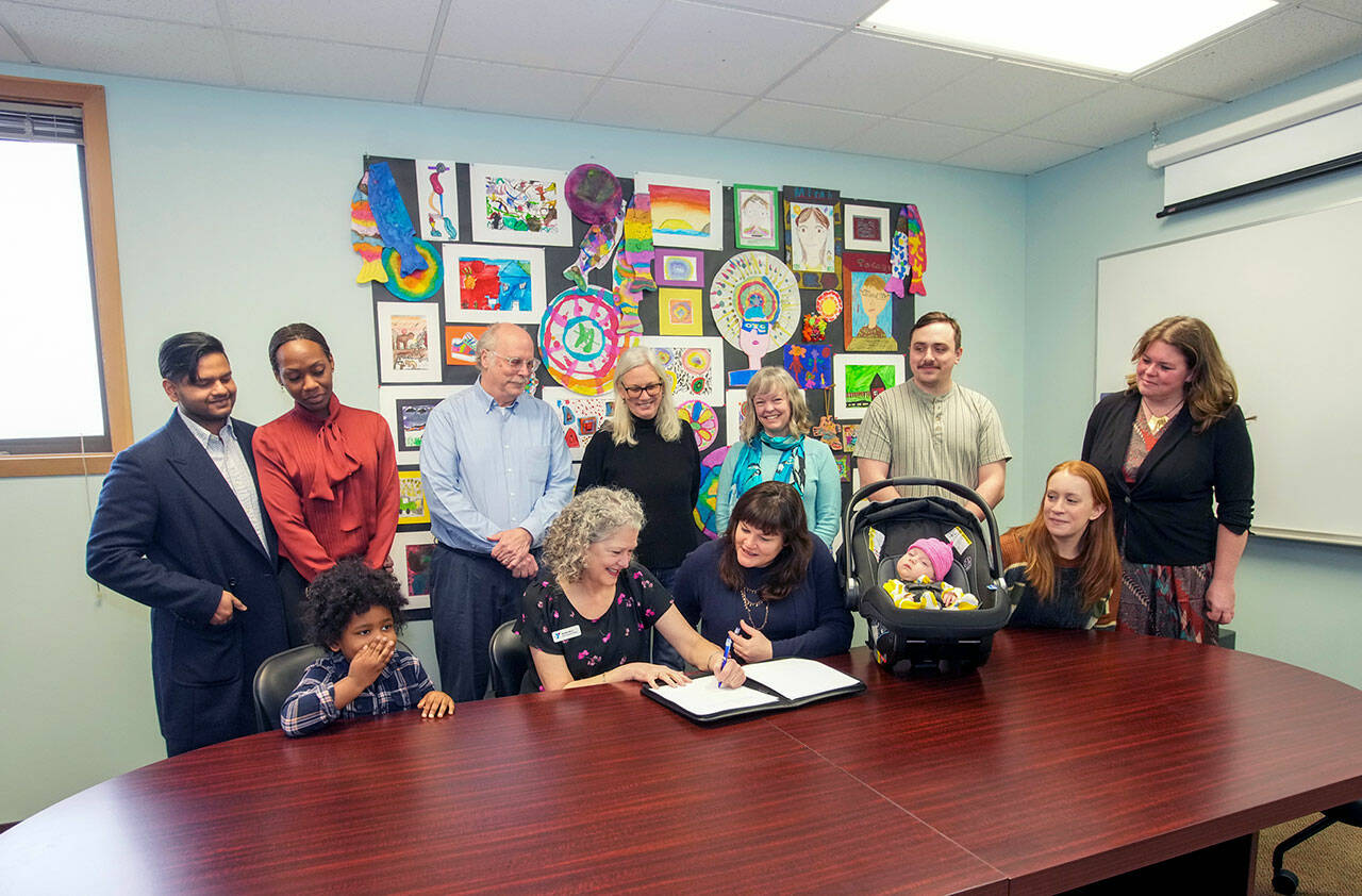 Steve Mullensky/for Peninsula Daily News
Wendy Bart, representing the YMCA, signs a lease for a lot on the Port Townsend School property to be used as a Jefferson County Early Learning and Family Support Center at a signing on Thursday at the administration office of Port Townsend School District. School superintendent, Linda Rosenbury, center front, had just affixed her signature to the lease. Also on hand were 4 year old Azan Luqman, with his parents behind him, Asif Luqman and Shawnisa Francis. Behind Bart are school board directors John Nowak and Jennifer James-Wilson, Dr. Molly Parker, representing Jefferson Healthcare, Alex Hankle, 7 week old Juniper, Nicole Hankle and Jefferson County supervisor Kate Dean.