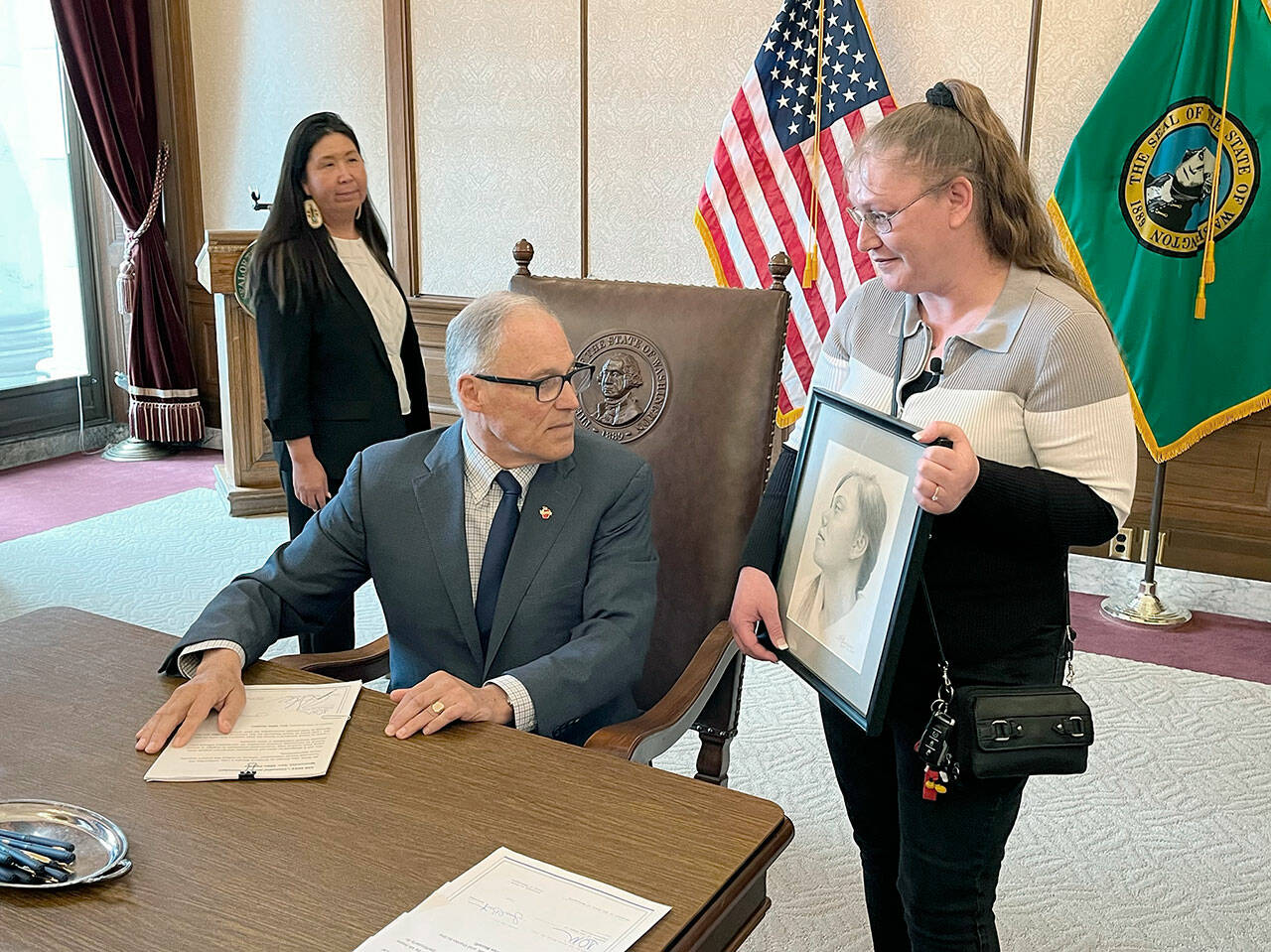 Dawn Reid, right, shows Gov. Jay Inslee a pencil drawing of her daughter, Kimberly, after Inslee signed a bill titled with Kimberly’s name. State Rep. Debra Lekanoff, left, took part in the ceremony. (Gabe Galanda)