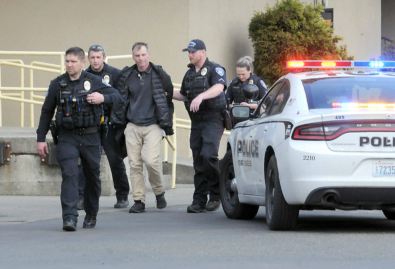 Police escort a man, center, who was alleged to have brandished a gun in the 48º North Waterfront Restaurant next to the Red Lion Hotel on Saturday. The incident prompted evacuation of the restaurant while closing down the 100 block of North Lincoln Street. (Keith Thorpe/Peninsula Daily News)