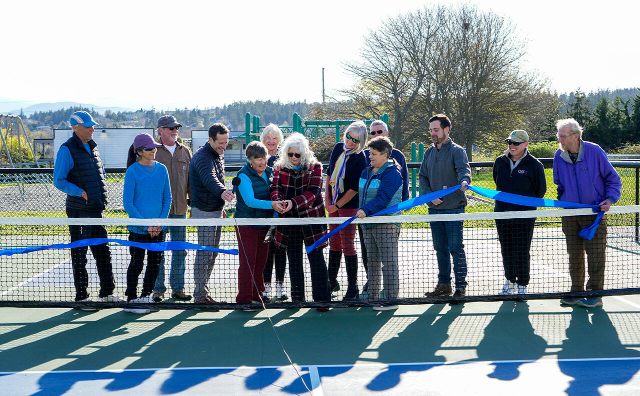 Port Townsend city council member, Monica Mick-Hagger and Port Townsend Pickleball Club president Lynn Pierle (cq) cut the ribbon to dedicate the Mountain View Pickleball courts to the City of Port Townsend in a ribbon cutting on Wednesday at the club. Others looking on are members of the club board of directors and city manager John Mauro, holding the microphone, Carrie Hite, Director of Parks and Recreation strategy, holding the ribbon and to her left is director of parks facilities, Michael Todd. The club now has 219 members on the roster. (Steve Mullensky/for Peninsula Daily News)