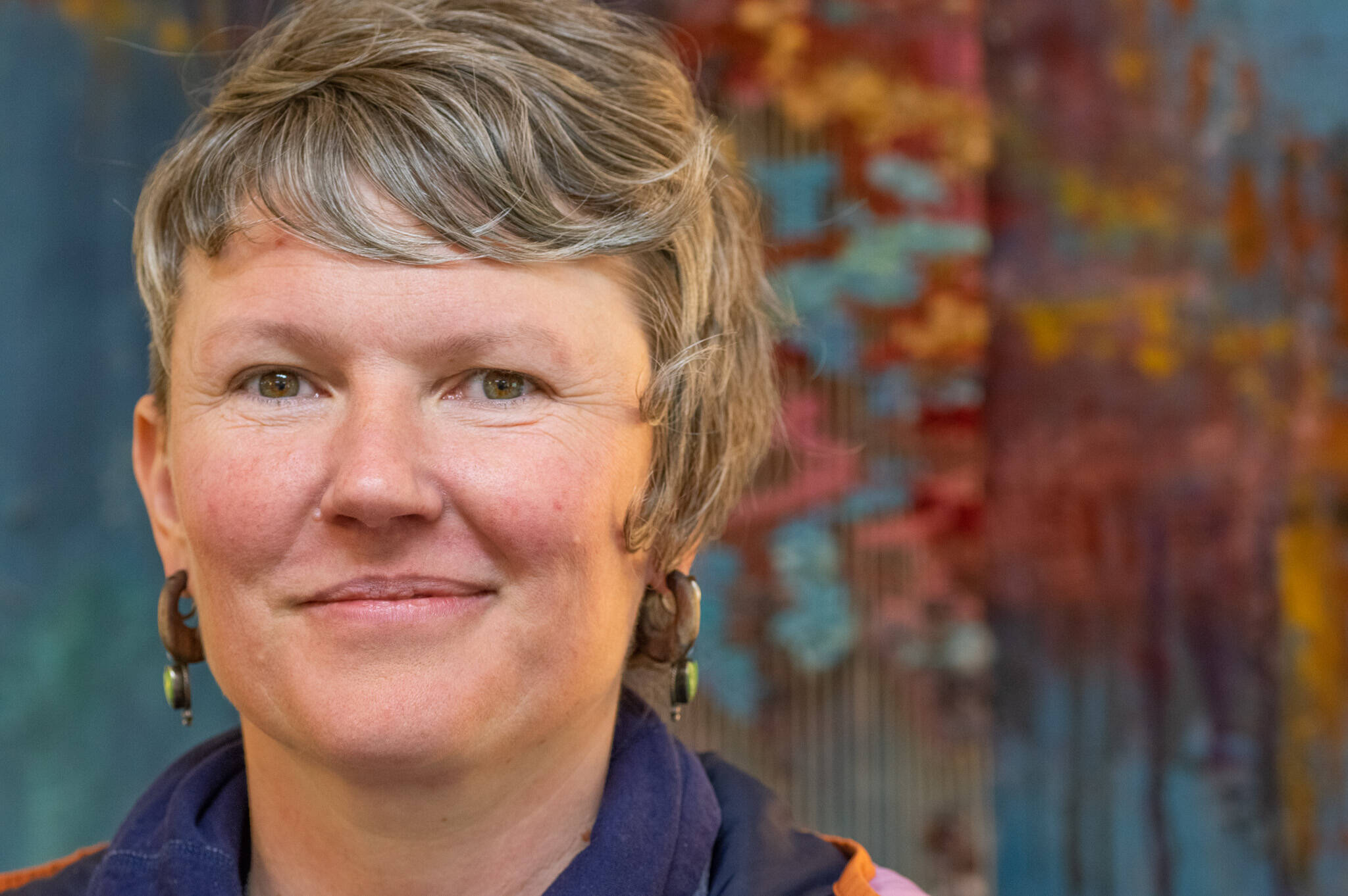 Emily Matthiessen/Olympic Peninsula News Group

 Artist Emily Carlquist, seen here before one of her abstract multi-media pieces featuring acrylic paint on textured canvas with needle-woven local fiber warped on canvas, on display at Dandelion Botanical for the month of April.