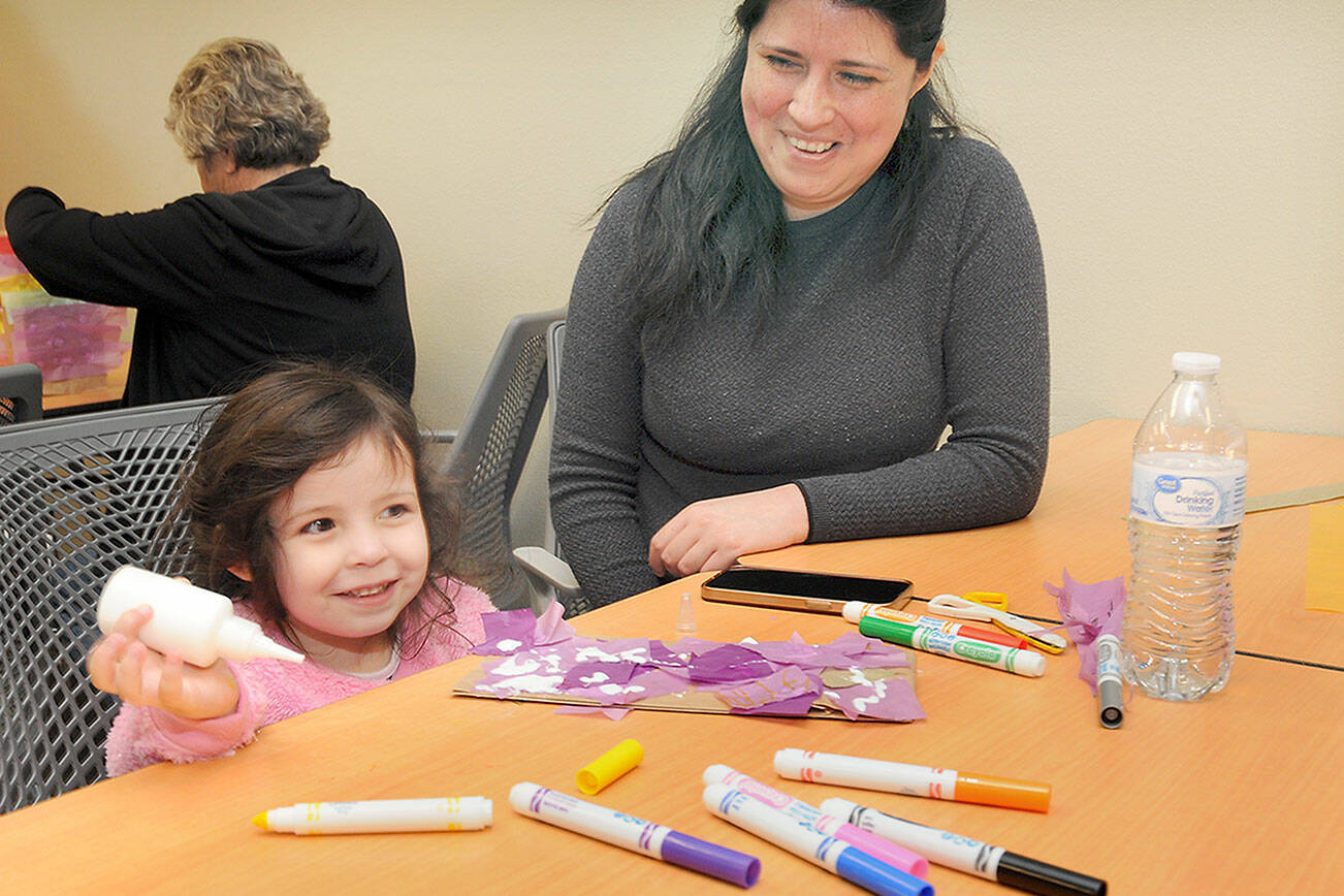 Arya Morrison, 3, grins while creating an art project as her mother, Janeth Morrison of Port Angeles, looks on during Saturday’s Dia del Niño, or Day of the Child, at the Port Angeles Public Library. The event, based upon an annual celebration in Mexico, was created to recognize the importance of children in society and to promote youth literacy. (Keith Thorpe/Peninsula Daily News)