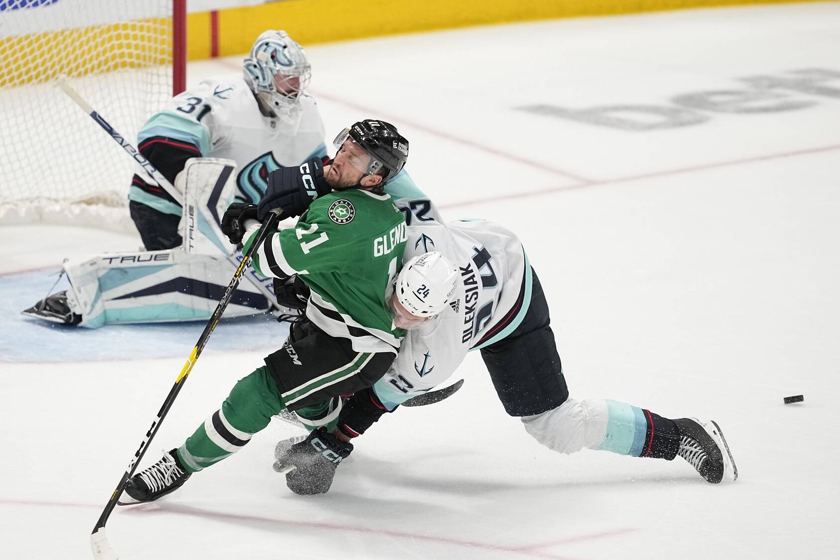 Dallas Stars center Luke Glendening (11) is knocked down on an attack by Seattle Kraken defenseman Jamie Oleksiak (24) as  Kraken goaltender Philipp Grubauer (31) defends against the puck in the third period of Game 7 of an NHL hockey Stanley Cup second-round playoff series, Monday, May 15, 2023, in Dallas. (AP Photo/Tony Gutierrez)