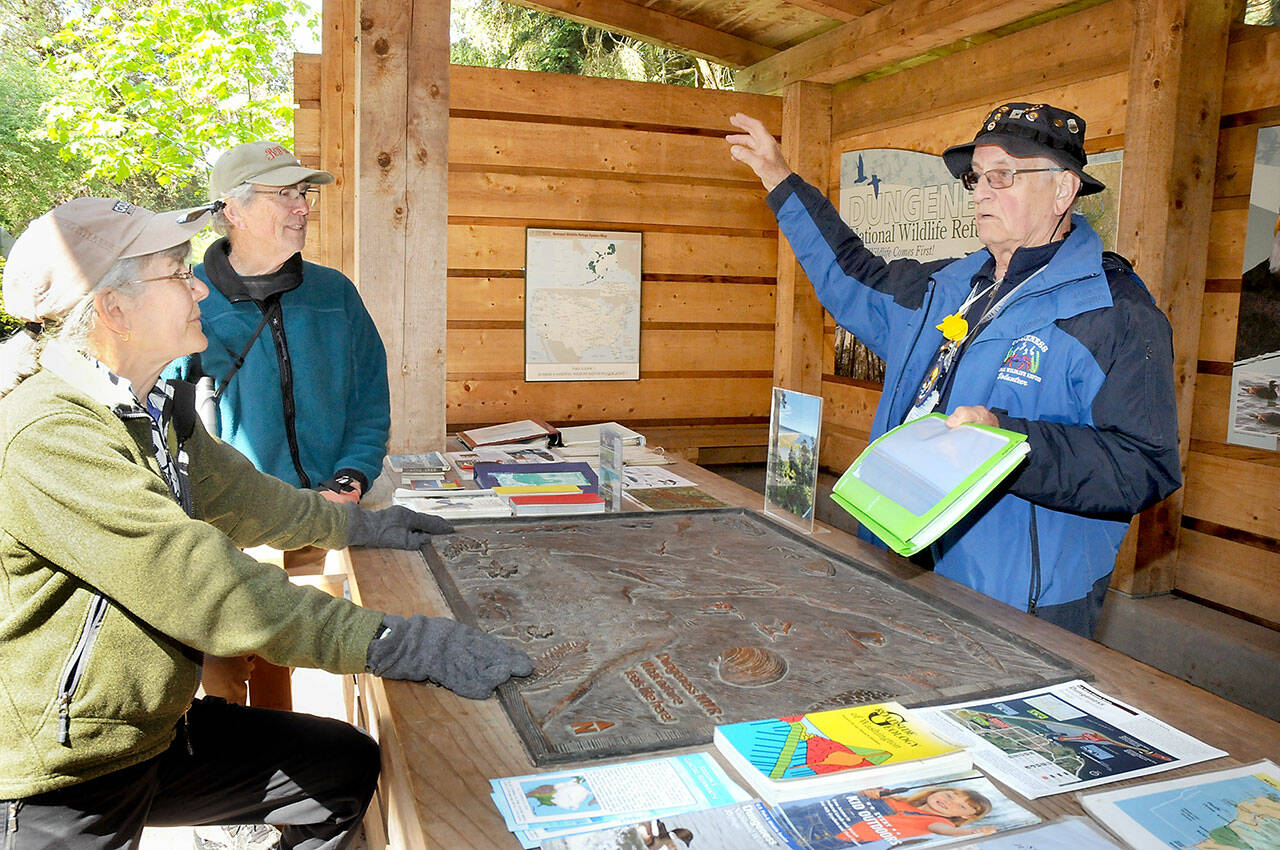 Martin Gutowski, a volunteer with the Dungeness National Wildlife Refuge, right, discusses features and attractions of the North Olympic Peninsula with Jan and Bob Tivel of Anacortes at the refuge’s information kiosk northwest of Sequim. (KEITH THORPE/PENINSULA DAILY NEWS)