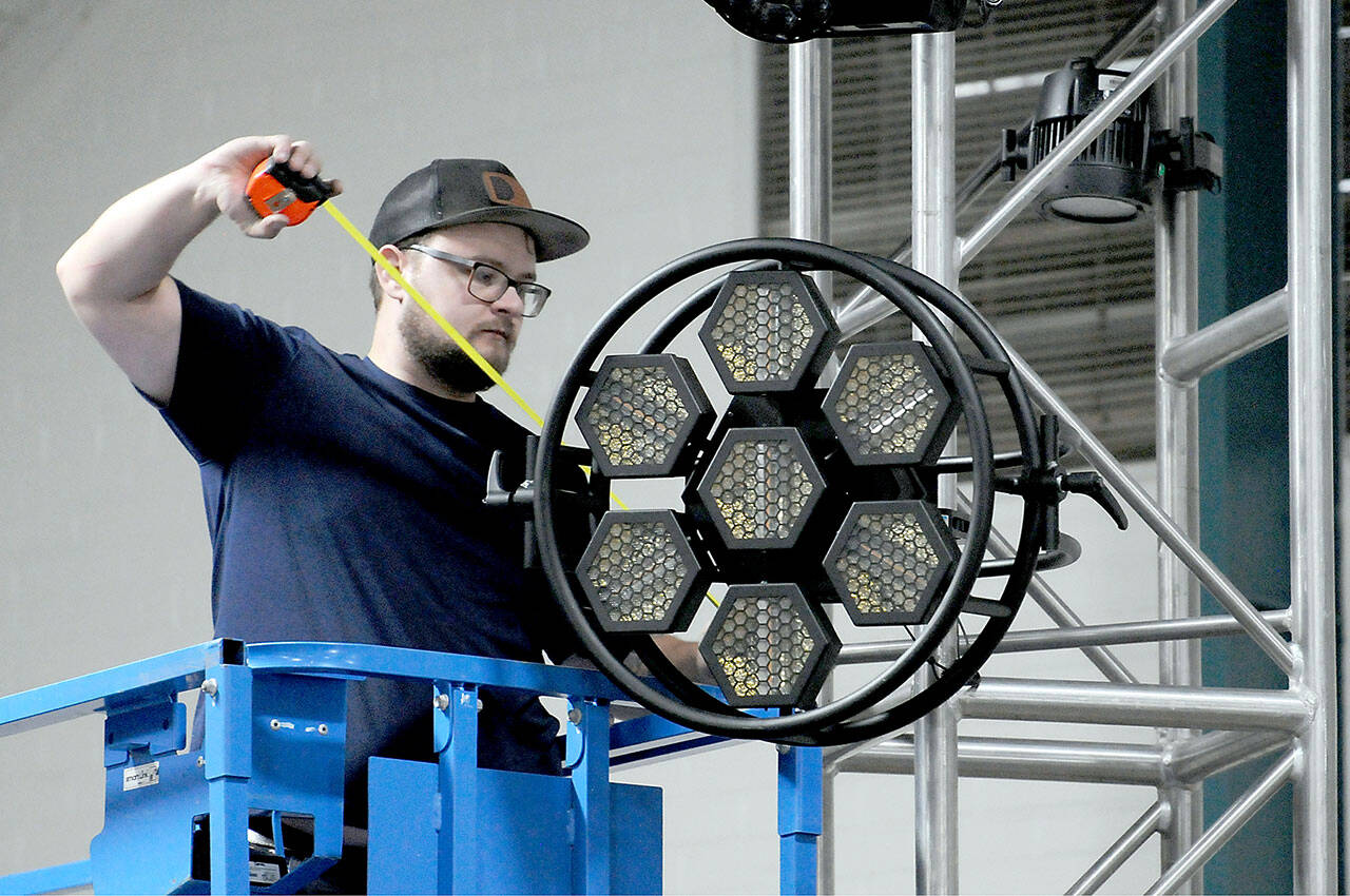 Levi Plumb of Seattle-based R90 Lighting adjusts a stage light on the Main Stage on Thursday in Vern Burton Community Center for this weekend’s Juan de Fuca Festival of the Arts. (KEITH THORPE/PENINSULA DAILY NEWS)