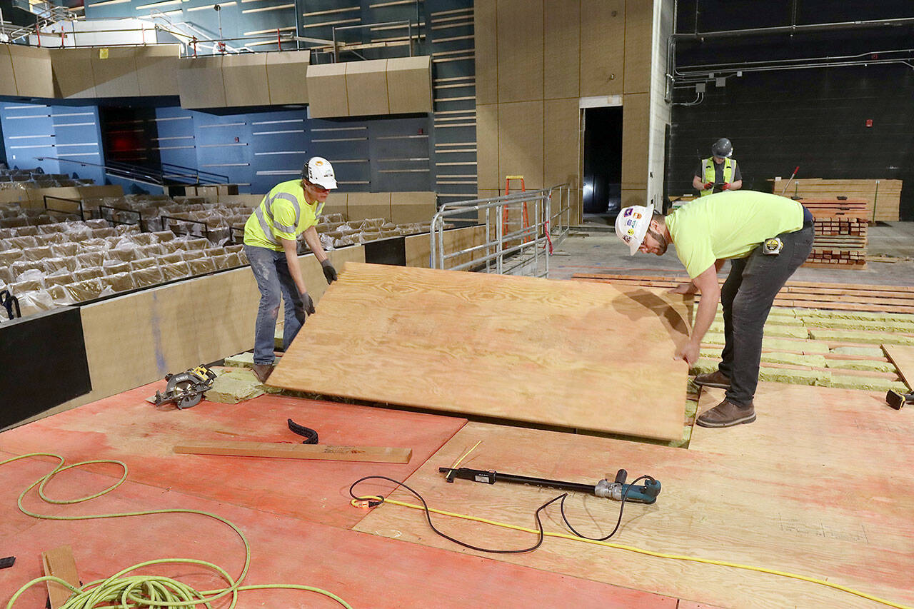 Matthew Sacks, left, and Levi Smith of Brandsen Co. from Portland, Ore., lay one of the layers on the new stage floor at the Field Arts and Events Hall in downtown Port Angeles. There will be a total of six layers of materials for the high-tech stage floor. The venue, which will seat 500, will begin to host performances when it opens at the end of July. (Dave Logan/for Peninsula Daily News)