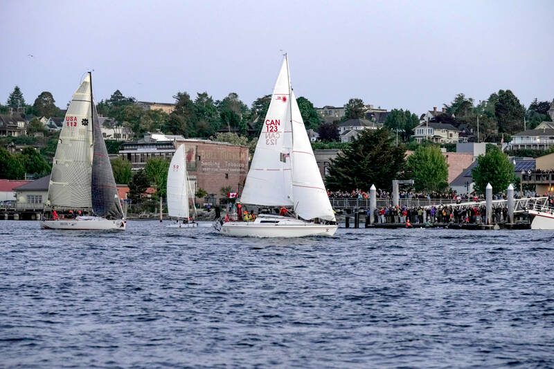 Racers in the Race to Alaska pass by the cheers and well wishes from the hundreds of spectators lining the docks at the Northwest Maritime Center when the cannon went off at 5 a.m. Monday, starting the 750-mile journey from Port Townsend to Ketchikan, Alaska. (Steve Mullensky/for Peninsula Daily News)