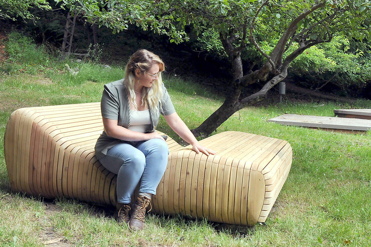 Rachel Storck, community engagement director for the Port Angeles Fine Arts Center, sits on the art installation “Sky Gazer” by Port Angeles artist Steve Belz, one of several new artworks in the Webster’s Woods Sculpture Park, the site of this weekend’s Summertide Solstice Arts Festival. (Keith Thorpe/Peninsula Daily News)