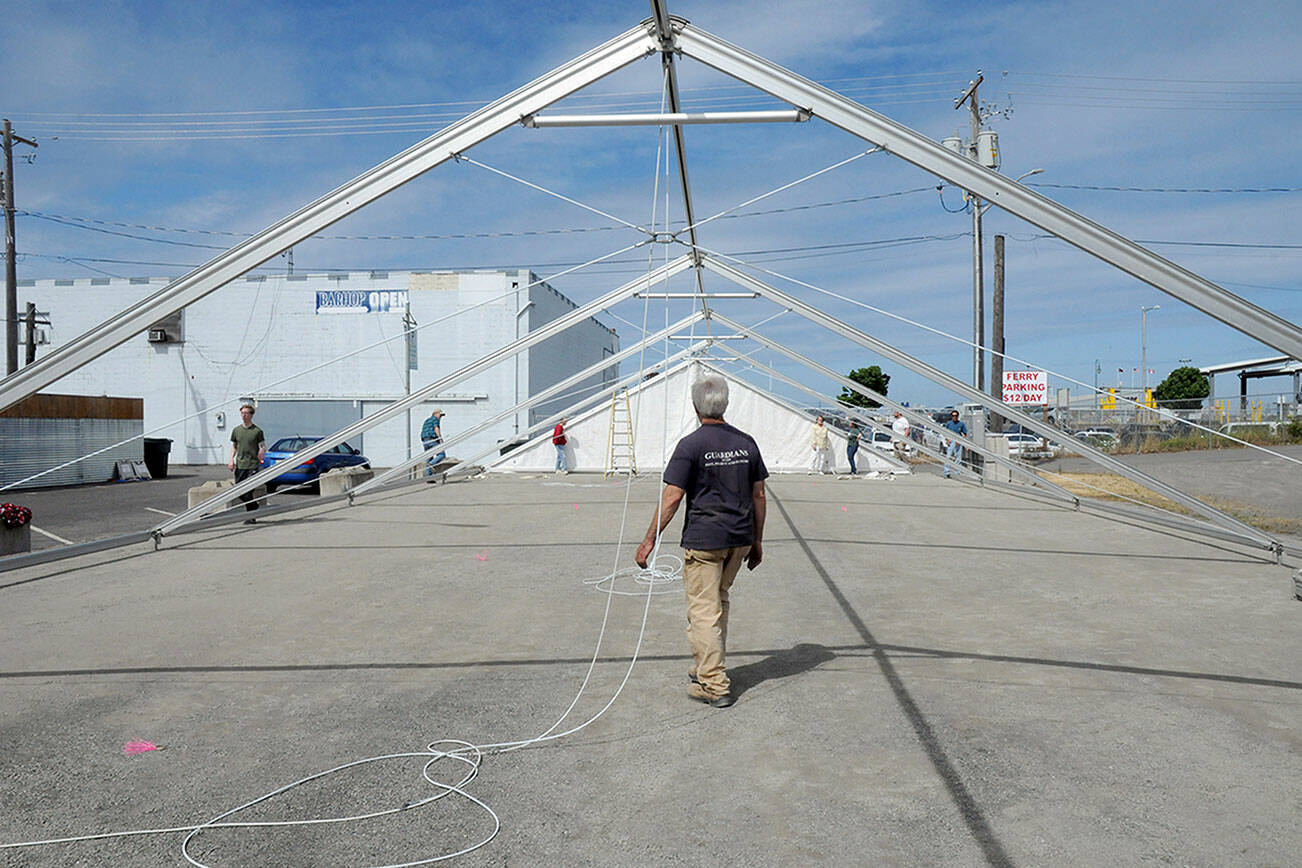 KEITH THORPE/PENINSULA DAILY NEWS
Steve Hargis, a board member of the Port Angeles Chamber of Commerce, directs the alignment of an events tent on Thursday that will cover a temporary roller skating rink in downtown Port Angeles.