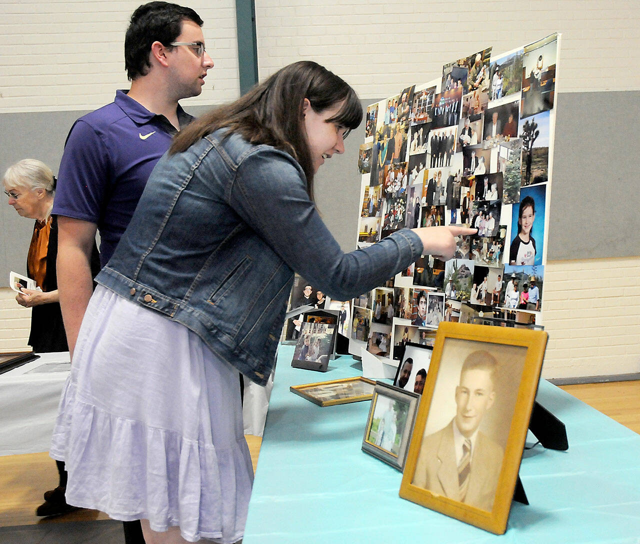 Ian Campbell of Bellevue, left, and Colette Campbell of Orlando, Fla., grandchildren of the late Port Angeles City Council member Orville Campbell, examine a table collection of family photos prior to a memorial service for the elder Campbell on Tuesday at Vern Burton Community Center in Port Angeles. (Keith Thorpe/Peninsula Daily News)