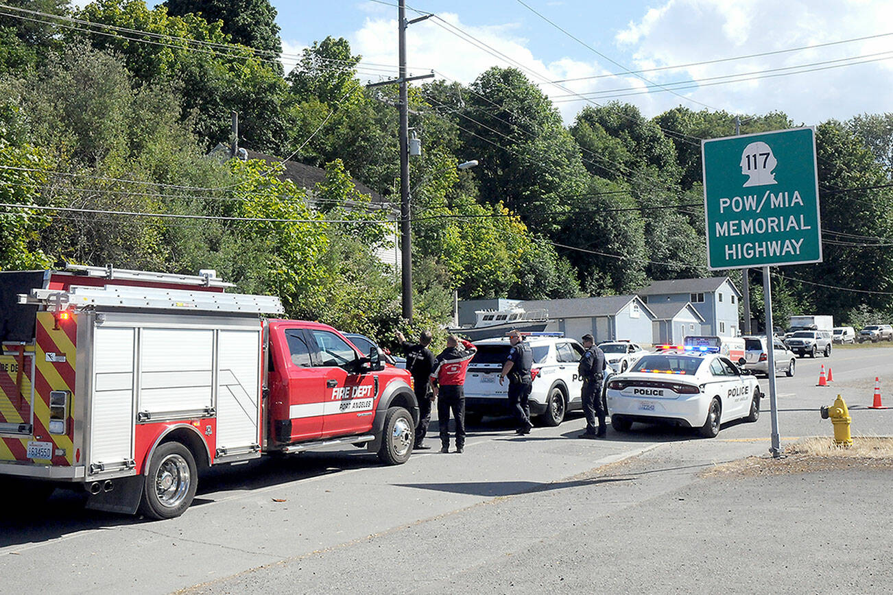 Port Angeles police and firefighters examine a utility pole and a downed powerline along the Tumwater Truck Route at Third Street that disrupted traffic and caused power outages on Wednesday afternoon. (Keith Thorpe/Peninsula Daily News)