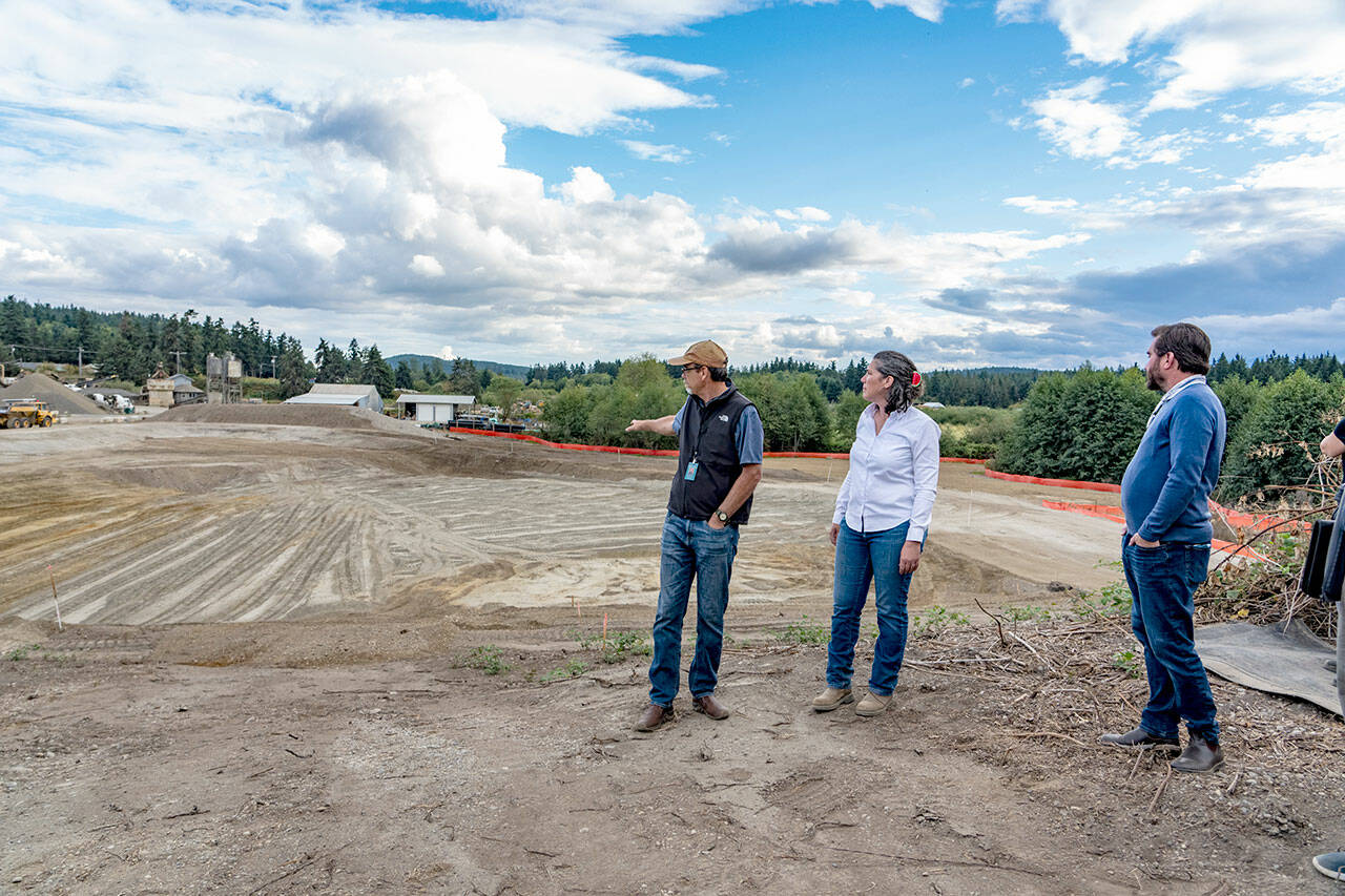 Jefferson County Public Works employee Monte Reinders, center, project manager Samantha Harper and county commissioner Greg Brotherton stand above the percolation pond for the new Port Hadlock sewer treatment facility that will be built along Loperman Road in Port Hadlock. The pond will treat, at its maximum, 700,000 gallons of treated wastewater per day. By the time the wastewater is treated and sent to this pond, it will be classified as class A reclaimed water, the highest category. The groundbreaking was held on Tuesday evening with about 35 guests on hand for the groundbreaking. (Steve Mullensky/for Peninsula Daily News)