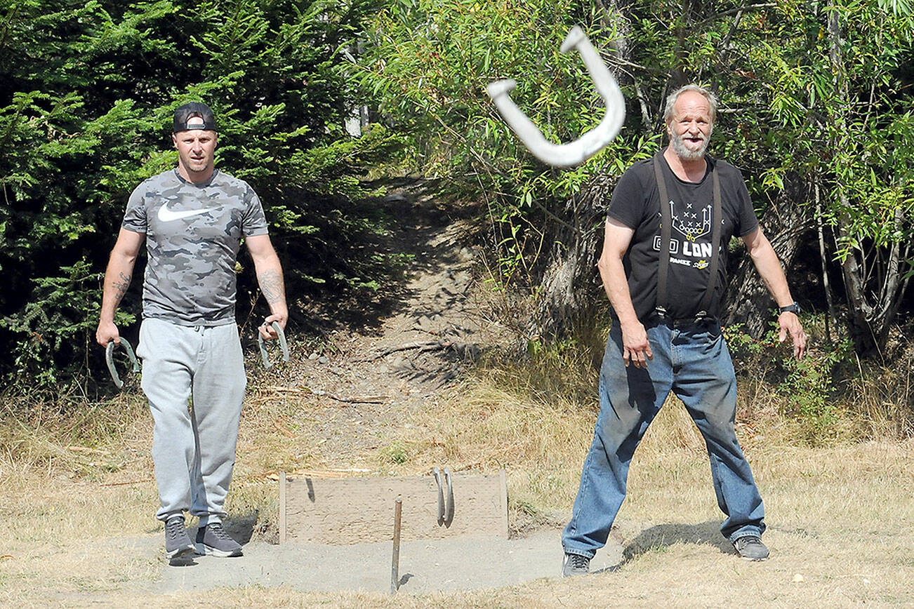 KEITH THORPE/PENINSULA DAILY NEWS
Mark Lingvall, right, throws a horseshoe as his son, Jeremy Lingvall, waits his turn during a game of horseshoes on Tuesday at Lincoln Park in Port Angeles. The Port Angeles men said they were frequent players of the game and bemoaned the fact that only two playable sets of pits still existed at the park.