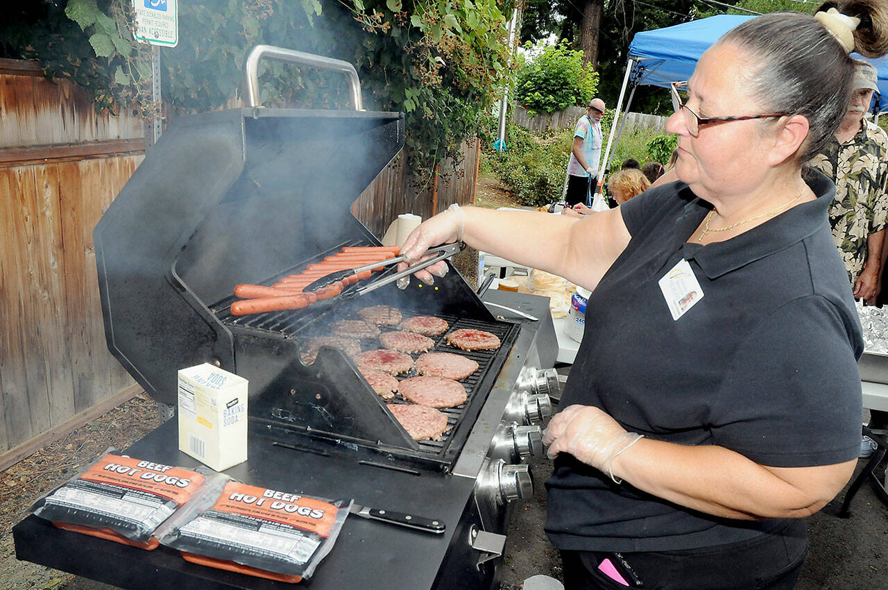 Diana Bossell, dietary manager with Peninsula Behavioral Health, grills hot dogs and hamburgers during a barbecue picnic and resource fair in honor of Overdose Awareness Day, observed on Thursday at Peninsula Behavioral Health’s Horizon Center in Port Angeles. The event, co-hosted by the North Olympic Healthcare Network, was designed to raise awareness of substance abuse and the effects of overdoses on victims and their families. Overdose Awareness Day included a rally at the Clallam County Courthouse and a remembrance march to Port Angeles City Pier. (KEITH THORPE/PENINSULA DAILY NEWS)