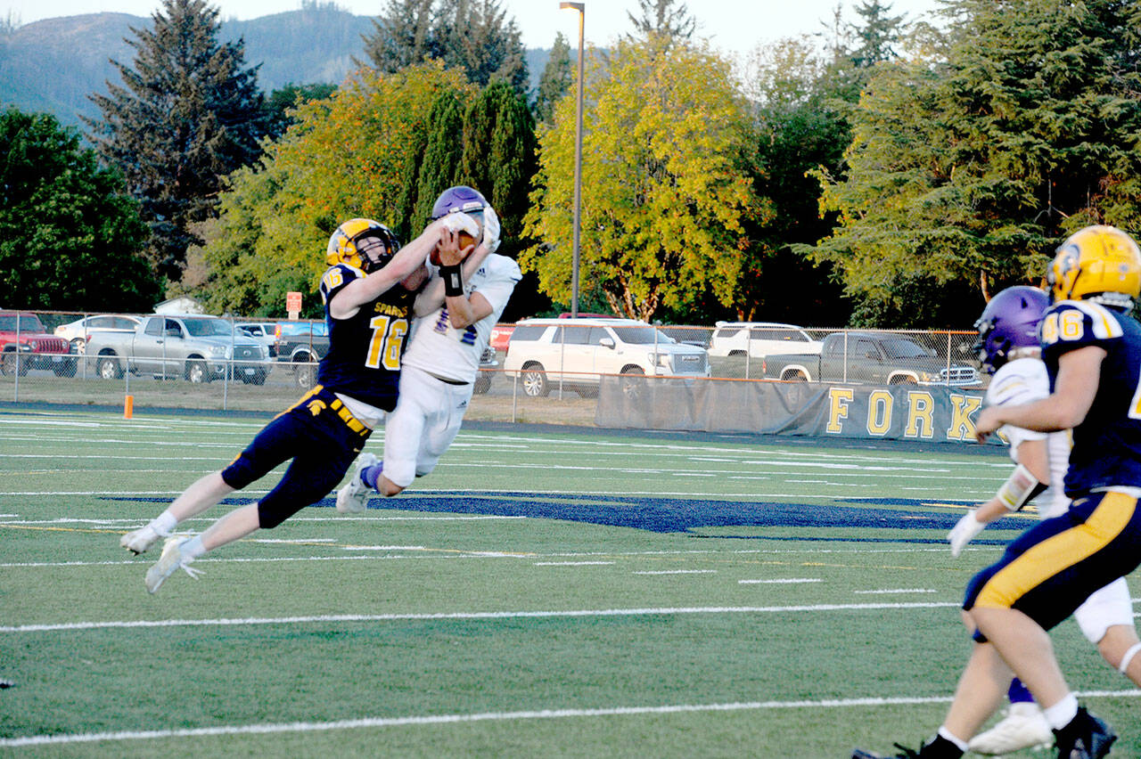 Forks’ Gunner Rogers (16) and Sequim’s Zeke Schmadeke (14) pull in a Forks pass for joint possession. Joint possession goes to the offense giving Forks a first down. (Lonnie Archibald/for Peninsula Daily News)