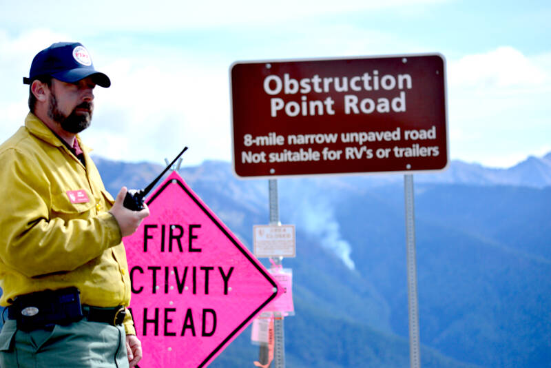 Mike Theune, Regional Fire Communication and Education Specialist with the National Park Service, listens to the radio at Hurricane Ridge on Wednesday as fire crews prepare for a helicopter to help move equipment out of the park. Several wildfires have been burning in Olympic National Park and firefighters are mostly letting the fires run their course.  (Peter Segall/Peninsula Daily News)