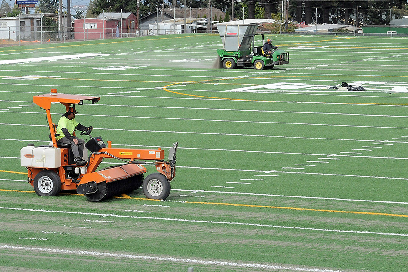 Tim Morland, front, and Rich Lear of Tualatin, Ore.-based Field Turf USA add fill to the playing surface at the new Monroe Athletic Field on Tuesday at the site of the former Monroe School near Roosevelt Elementary School in Port Angeles. The synthetic turf field, which is expected to be completed by mid-autumn, is being developed by the Port Angeles School District and will be available for community athletic events. (Keith Thorpe/Peninsula Daily News)